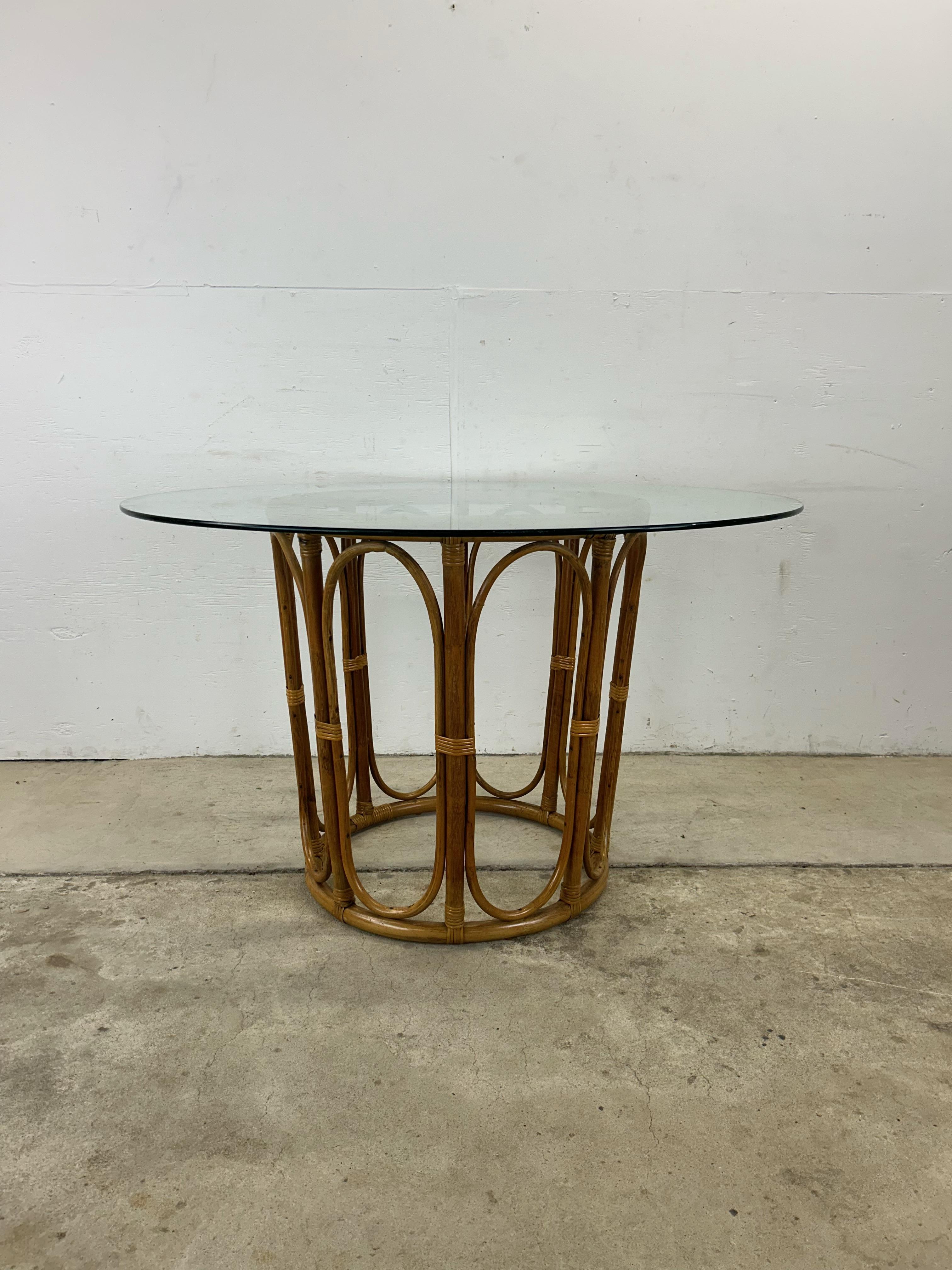 This vintage dining table features round glass top, rattan pedestal base with original finish.

Matching set of chairs and several similar rattan pieces available separately. 

Dimensions: 48.25w 48.25d 30h

Condition: Original rattan finish is in