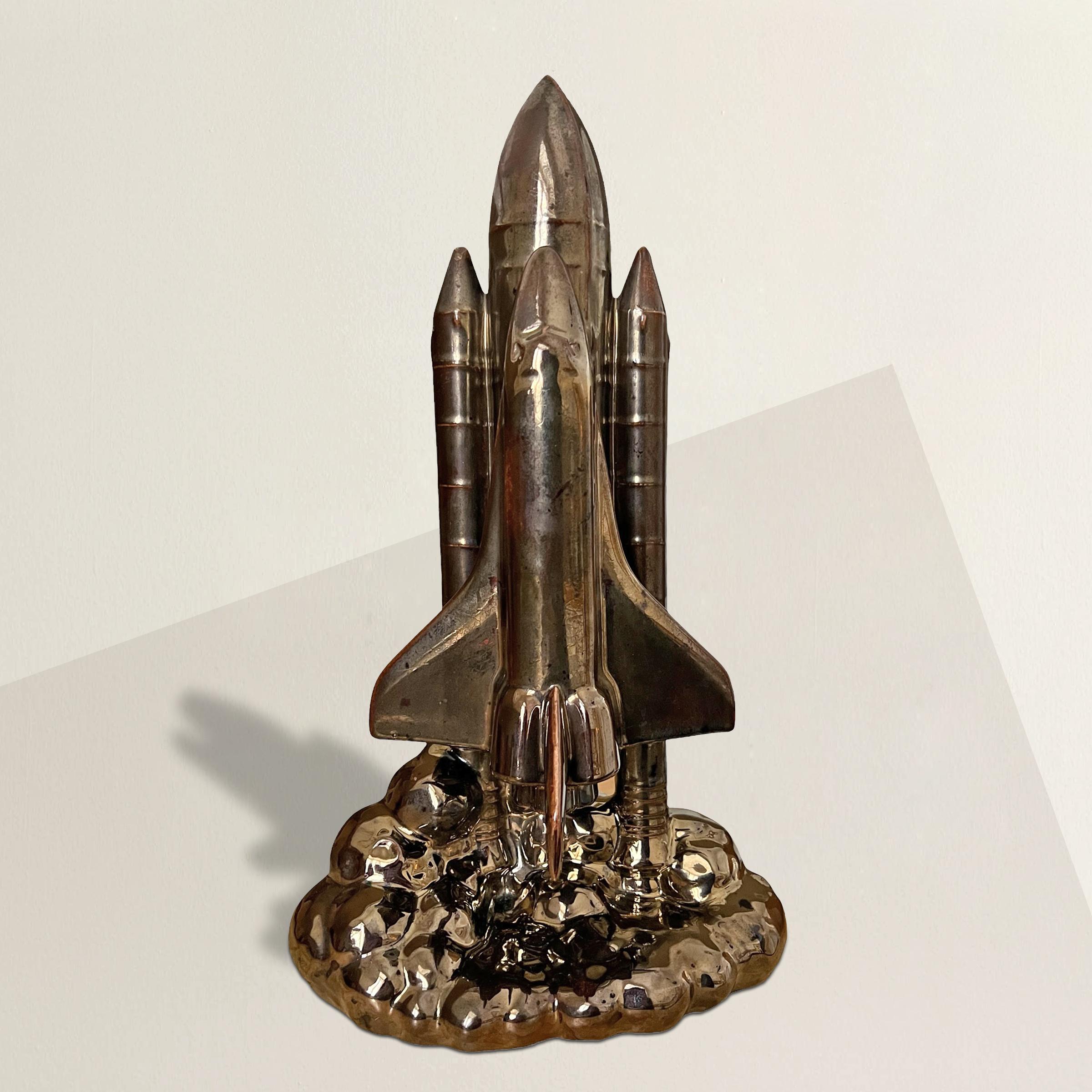 This mid-20th century American space-age porcelain sculpture is a striking ode to NASA's space exploration. Depicting a space shuttle in the initial stages of launch, the orbiter and boosters are dynamically supported by the billowing exhaust plume,