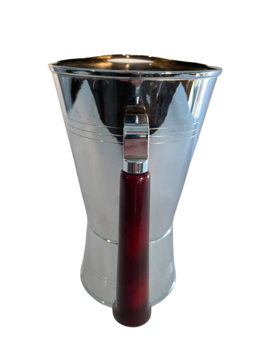 Chrome bar pitcher by Glo-Hill with red faux tortoiseshell Bakelite pistol grip handle. The pitcher with ice guard tapers from top to about a third from the bottom then flares out to the bottom.