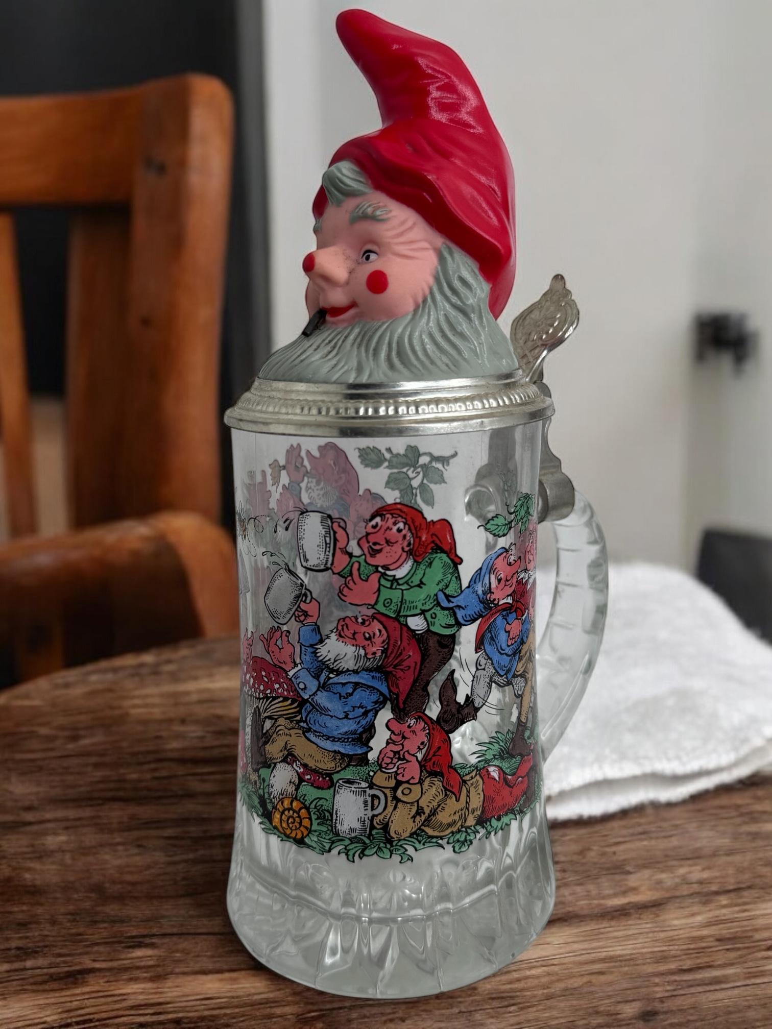 Un magnifique stein à bière en verre avec une tête de gnome et des images de gnomes sur le stein. Ce stein à bière a été fabriqué en Allemagne vers les années 1970 ou plus anciennement, marqué Allemagne. Il s'agit d'une gourde de 0,5 litre. Pièce