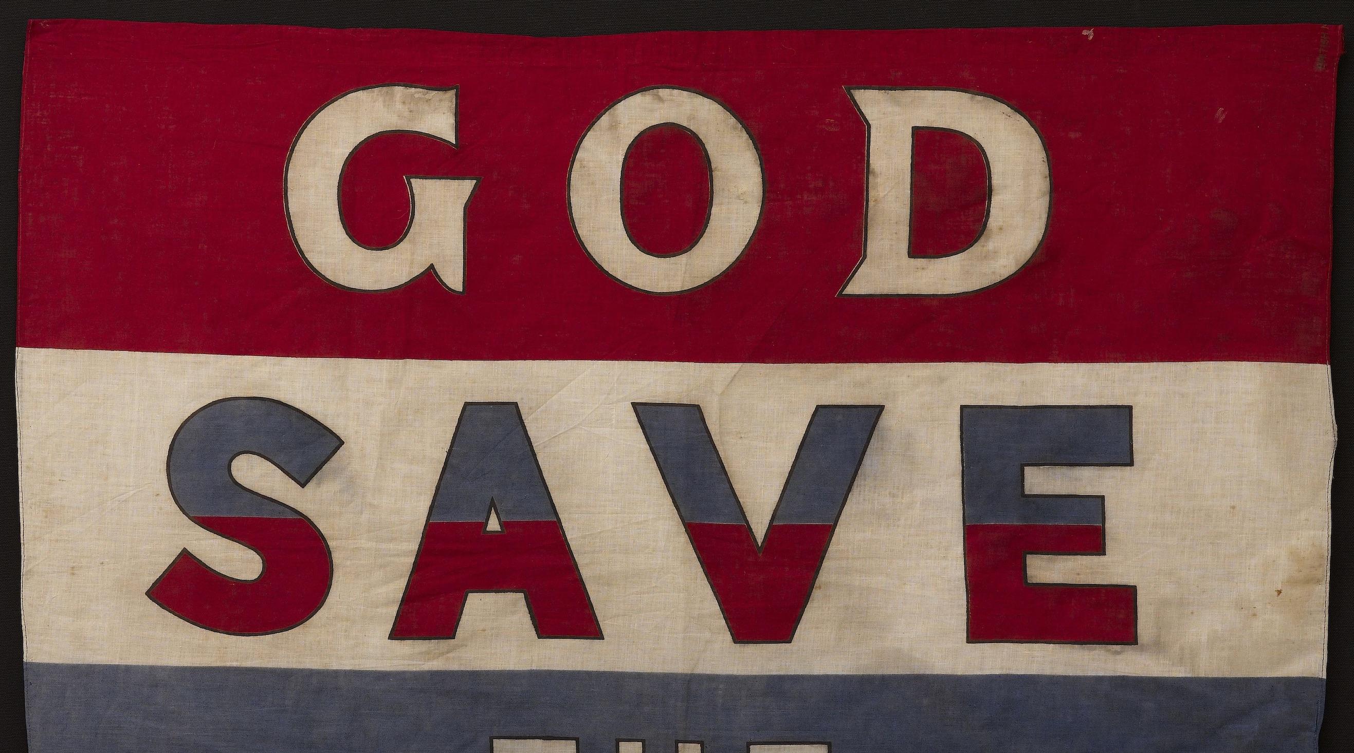 This vintage celebratory banner reads, “GOD SAVE THE KING” in bold white and split red and blue letters, set against a red, white, and blue striped field. This English-produced banner was printed sometime in the 1930s. 

“God Save the King”