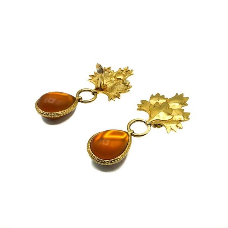 Vintage Amber Leaf Earrings. Crafted from gold plated metal and amber colored resin. Featuring a large leaf top with a vibrant amber teardrop. In very good vintage condition. 8cms. Signed. A super stylish pair of vintage statement earrings that will