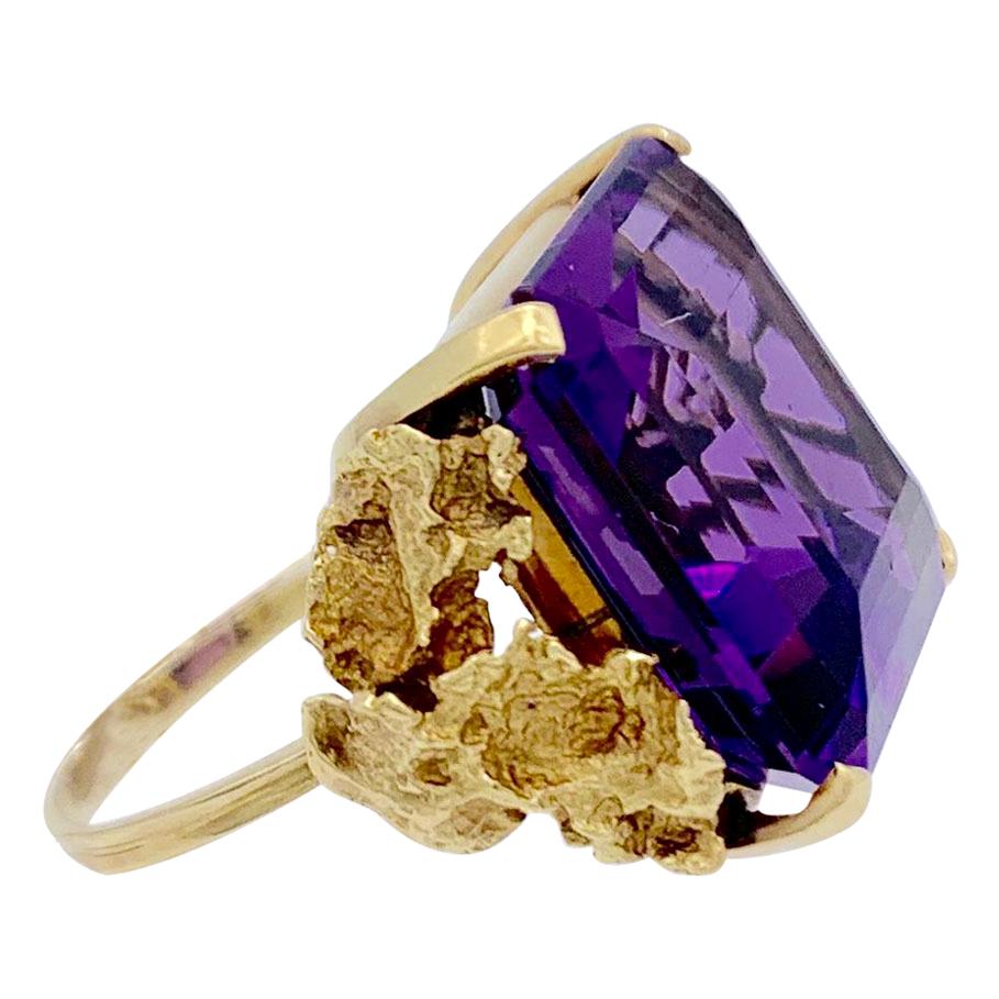 This stunning and elegant cocktail ring is set with a square step cut amethyst. 
The fine and bright stone with an established weight of 23 carats has been set in a mount reminiscent of gold nuggets.
The ring was made around 1950/1960.

Ring Size: