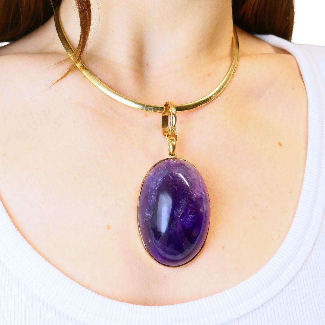 Diese Vintage-Halskette besteht aus einem italienischen Omega-Kropfband aus 14-karätigem Gelbgold und einem abnehmbaren Anhänger aus 18-karätigem Gelbgold mit einem markanten Amethyst-Cabochon. Das Kropfband hat ein hochglänzendes, gegliedertes