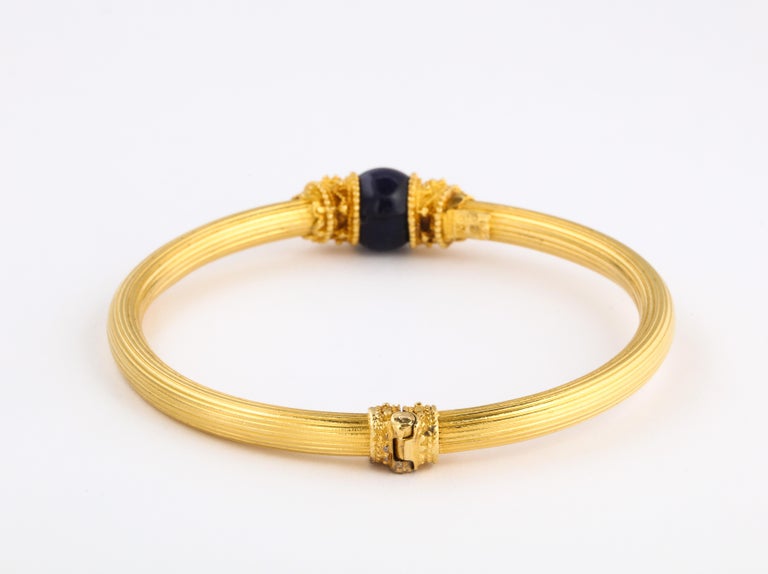 Ridges, like streams of 18Kt gold wrap this wrist of this Lalaounis lapis orb bracelet. The bangle opens by separating the lapis from the wristband as seen in the photograph. Granulation and raised wiring in the style of Hellenistic Byzantine