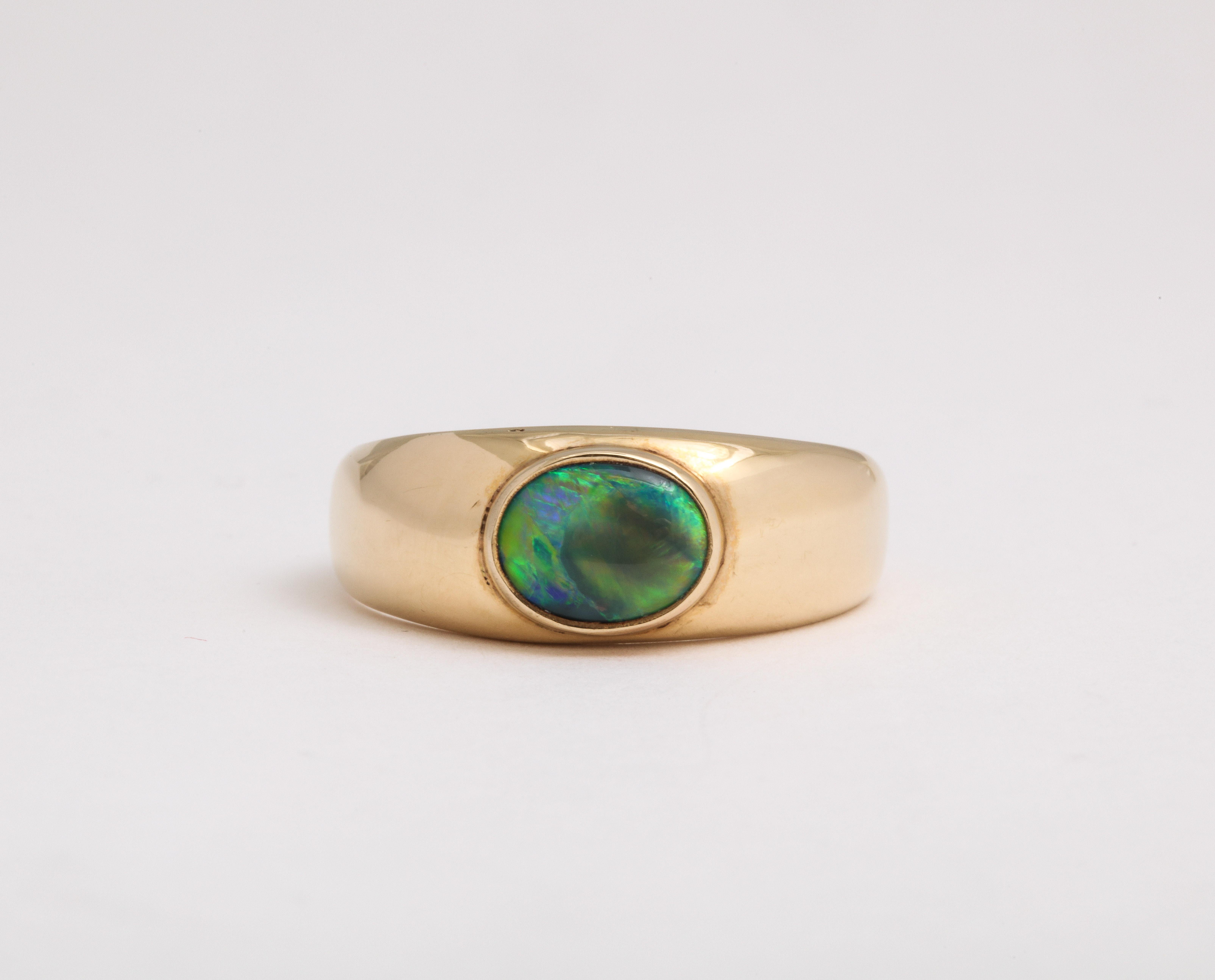 Set with a natural oval black opal of warm ocean blue green  color this ring is nature showing its most rare of the opal family.   There is a spectrum of color in this Australian opal,  a dark tone with flashings within of dark and light shades of