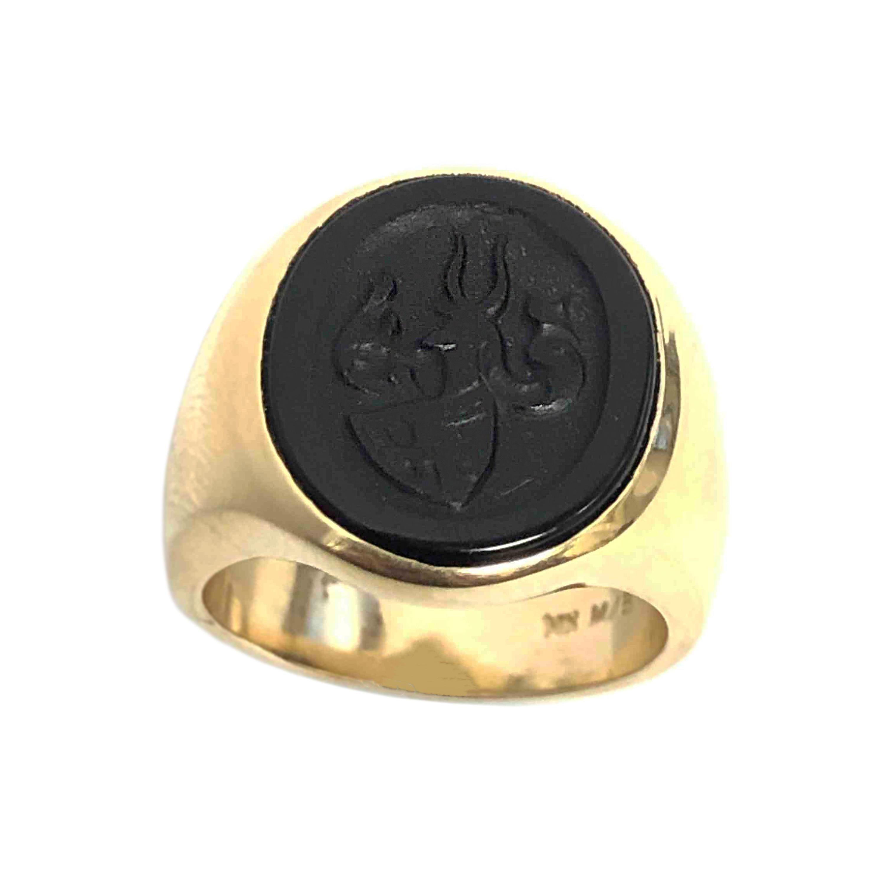 Circa 1930s Gents 14K Yellow Gold Signet Ring. Centrally set with an Oval Onyx measuring 5/8 X 1/2 inch and having a deep carving with a Shield and winged Insignia Crest. Finger size 6 1/2. 
