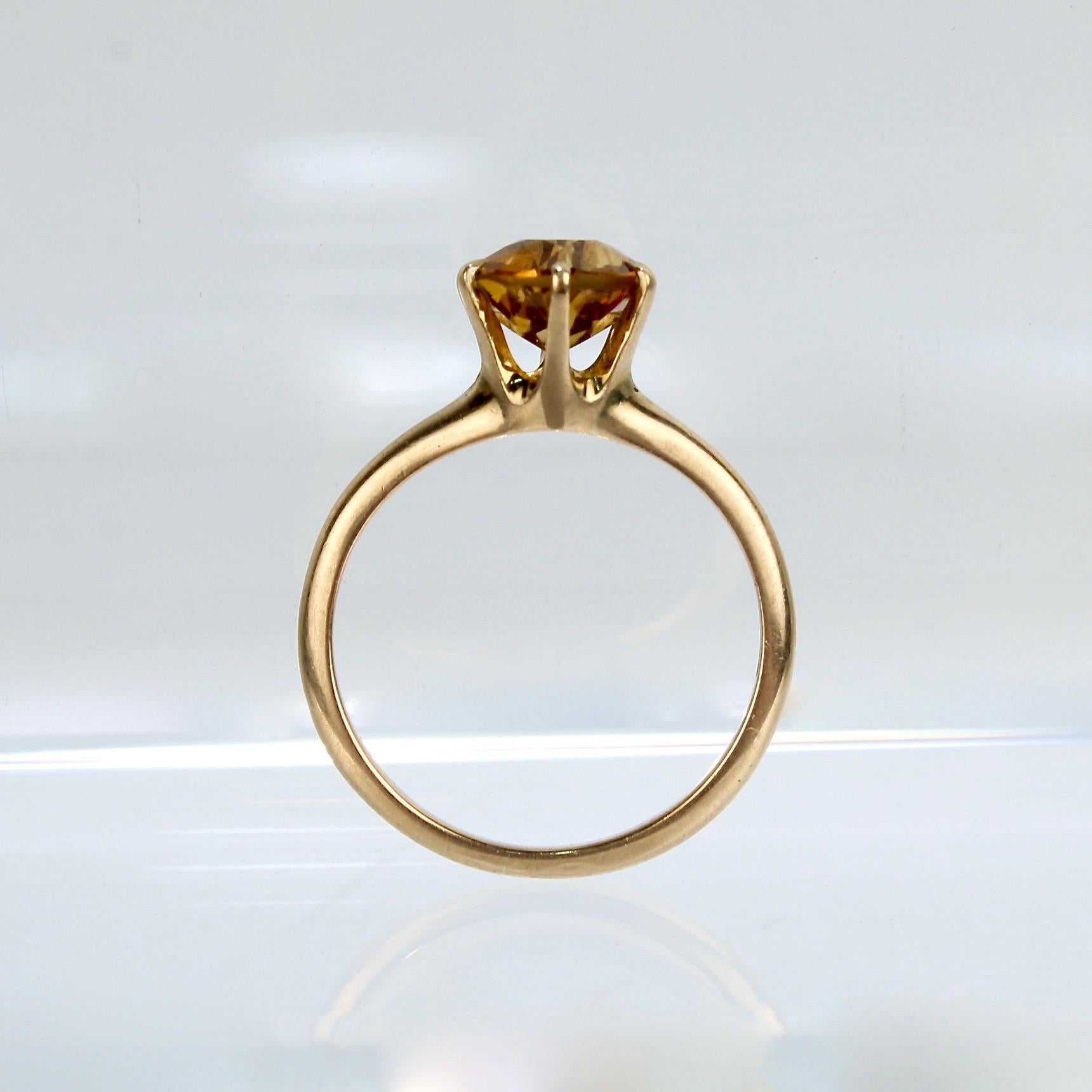 A fine 10K gold and citrine gemstone ring.

This simple band has a high prong set organe-toned, round-cut citrine solitaire gemstone.

Stamped TKB for the maker to the shank. Unmarked for gold fineness. Professionally tests at 10K.

A great vintage