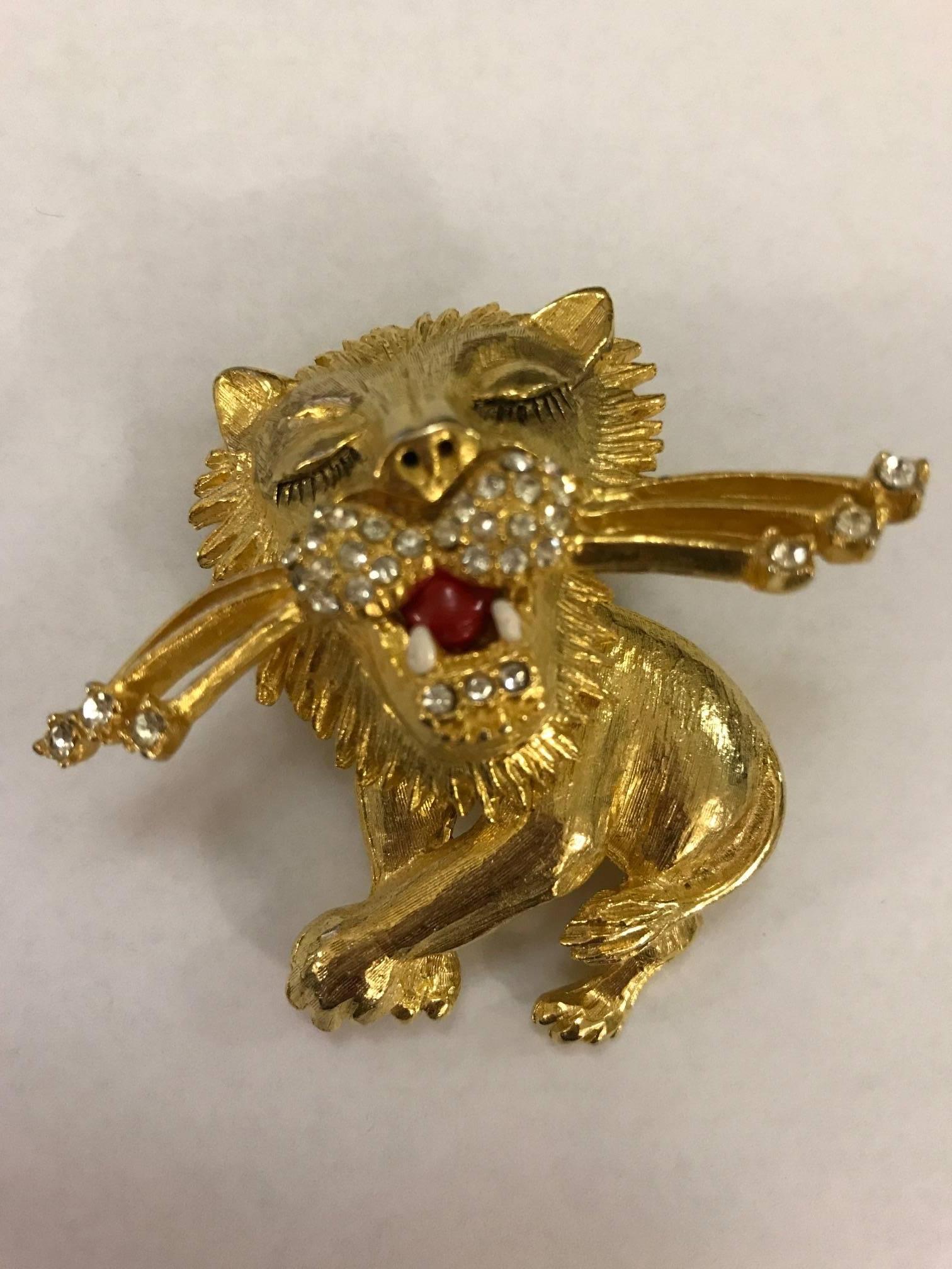 Gold tone vintage brooch features a rhinestone detailed lion prancing and batting his lashes.

Measures approximately 2 1/4