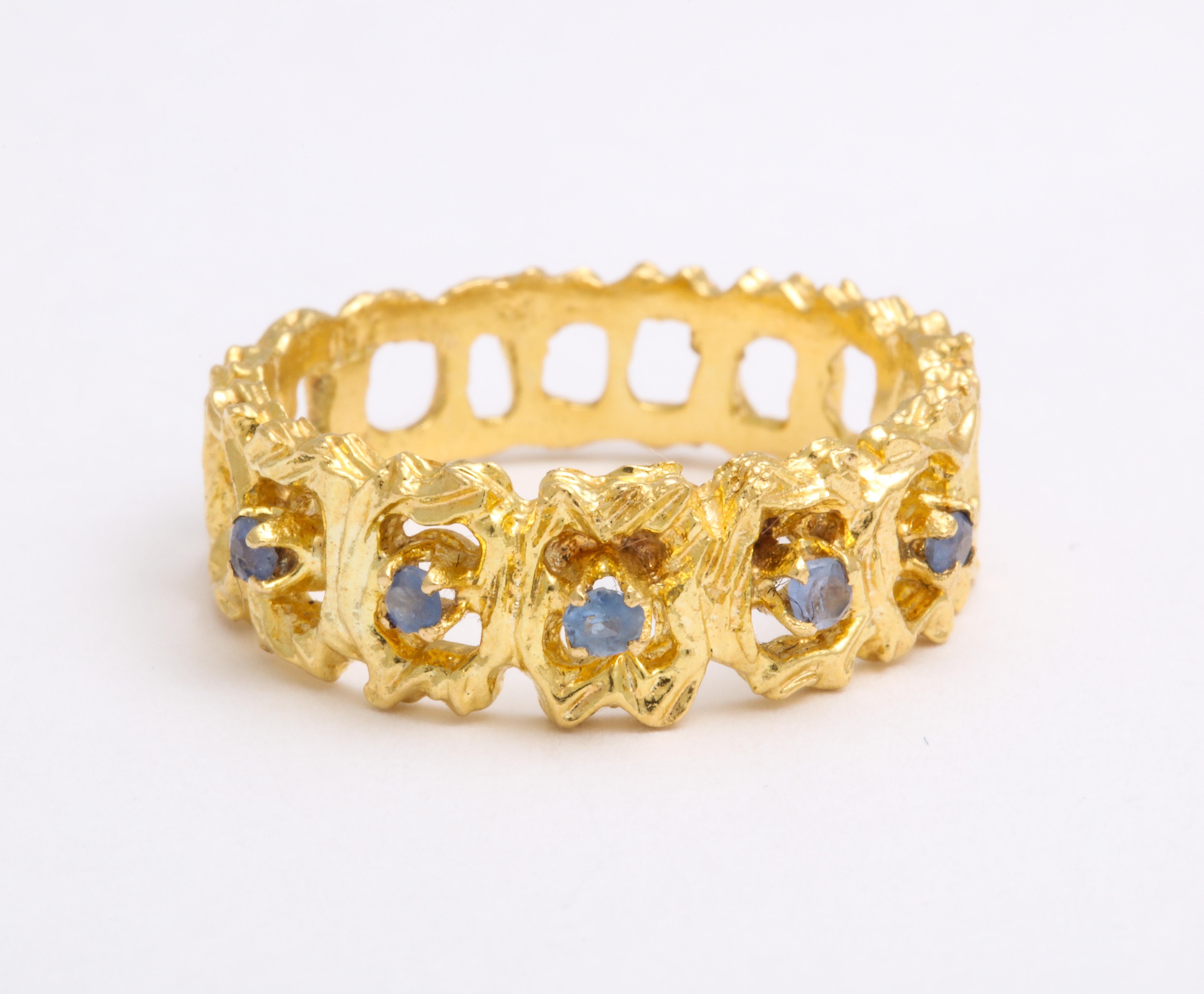 The heavens touch this 18 Kt gold band by setting twinkling blue Ceylon color sapphires around the lacelike face. The sapphires are small stones with few facets, no more than 3.5 points total weight yet their presence is just right for the space