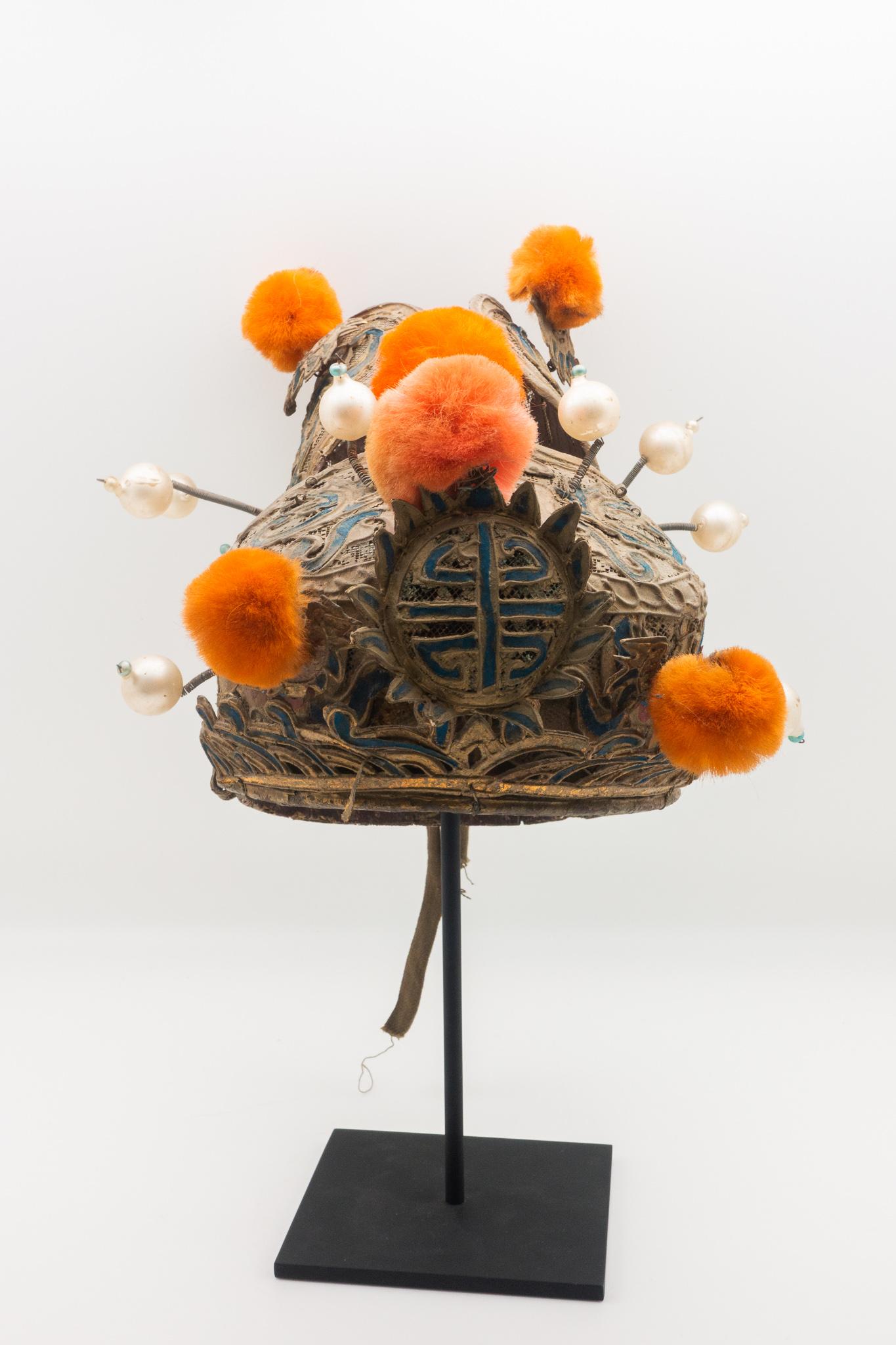 Vintage Chinese opera theatre headdress in turquoise and gold colors with orange pom poms.
Early 20th century, mounted on a custom, black painted metal base.