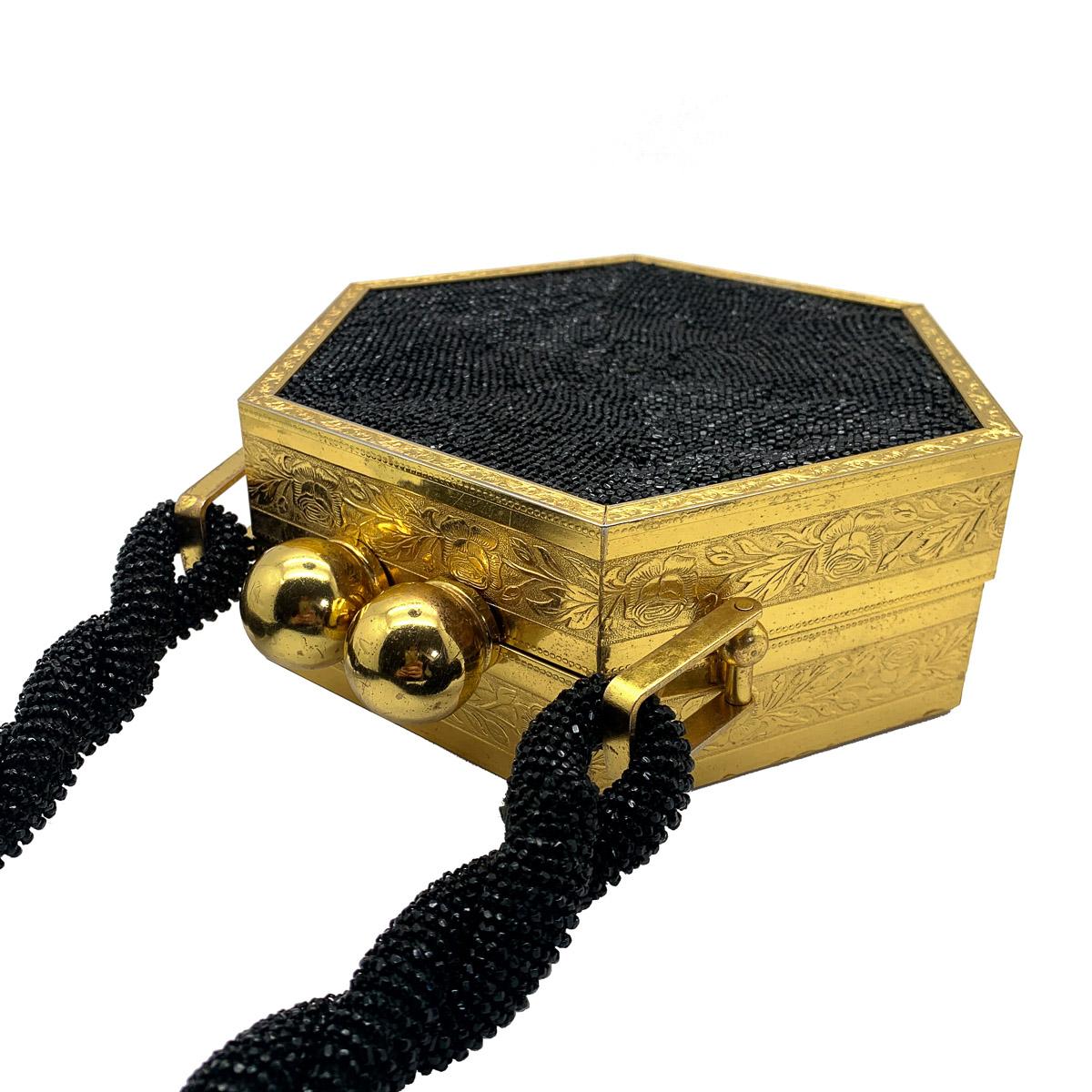 A stunning Vintage Gold & Black Minaudiere from the 1950s. In immaculate vintage condition inside and out. Featuring a large hexagonal box style bag with ornately chased sides and a wonderful black glass microbead front, back and handle. Finished to