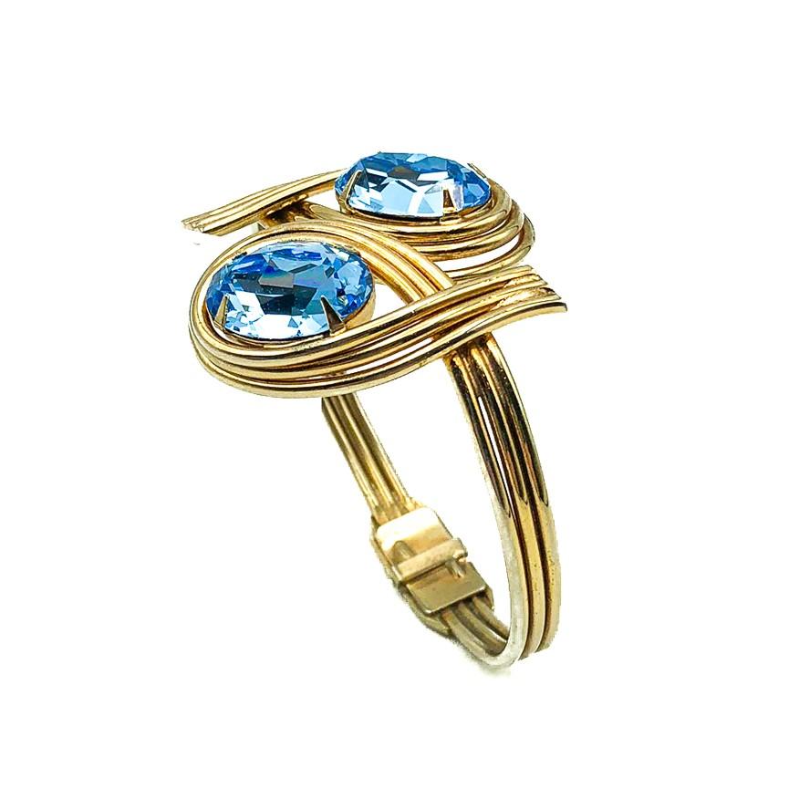 A striking Vintage Blue Crystal Clamper Bracelet. Featuring a double loop clamper style bangle set with the most gorgeous pair of large faceted blue, claw set, crystal stones. Crafted in gold plated metal and set with glass crystals. In very good