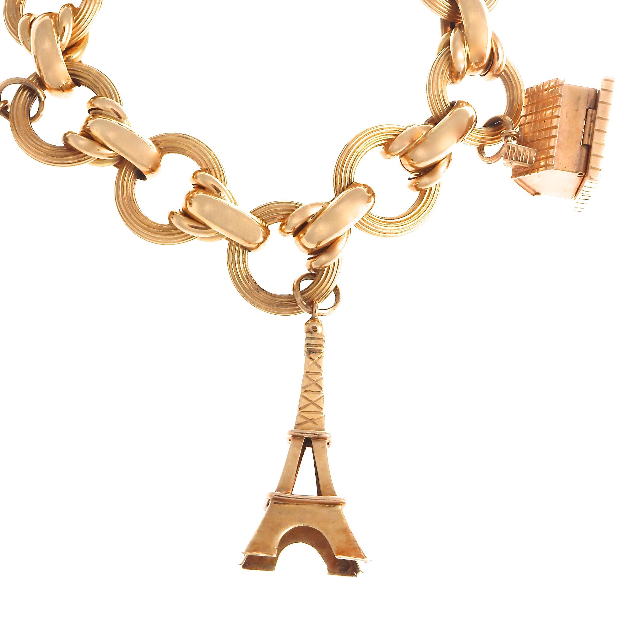 Chunky gold links are adorned with five unique and refined 18k gold charms. The items are a baby carriage, house, boot, Eiffel tower and a sexy pair of high heels.  A fun vintage charm bracelet from the 1960's  Weighs 45.5 grams.