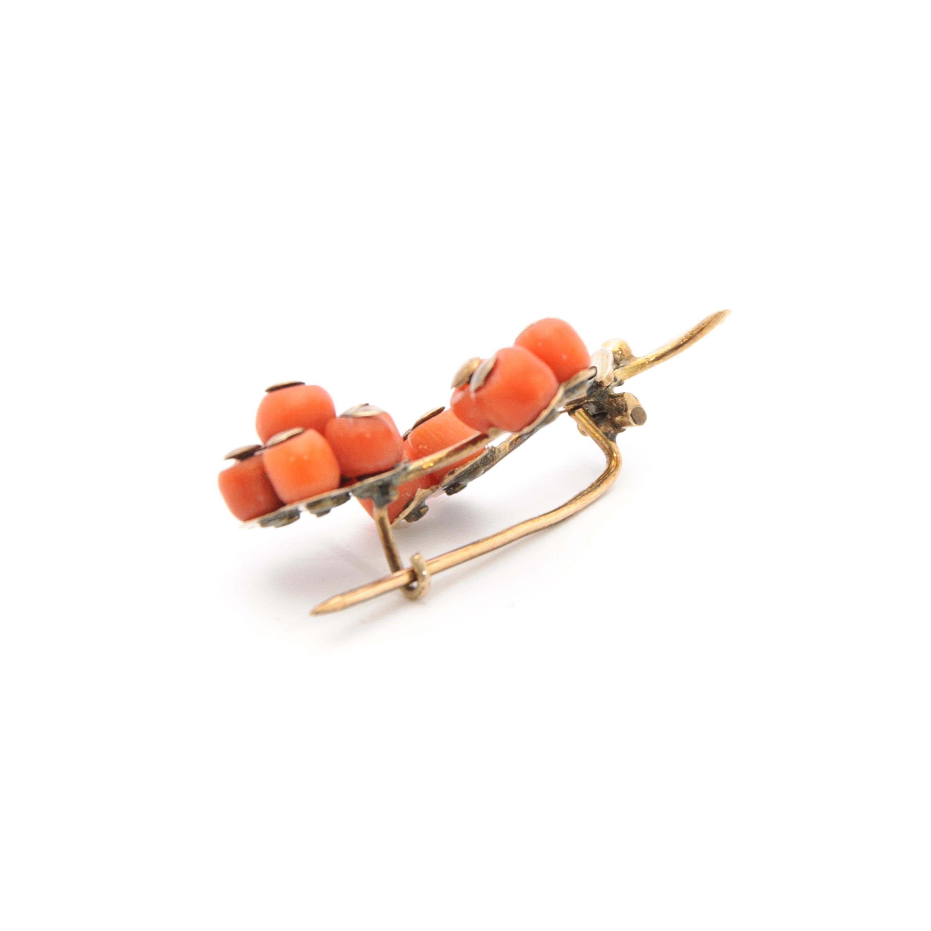 A vintage brooch composed of several small round beaded pieces of red, natural coral. It features a beautiful bouquet of thirteen red corals set on branches of gold. Each barrel-shaped coral bead has a gold cap on top to hold the bead at it's place.