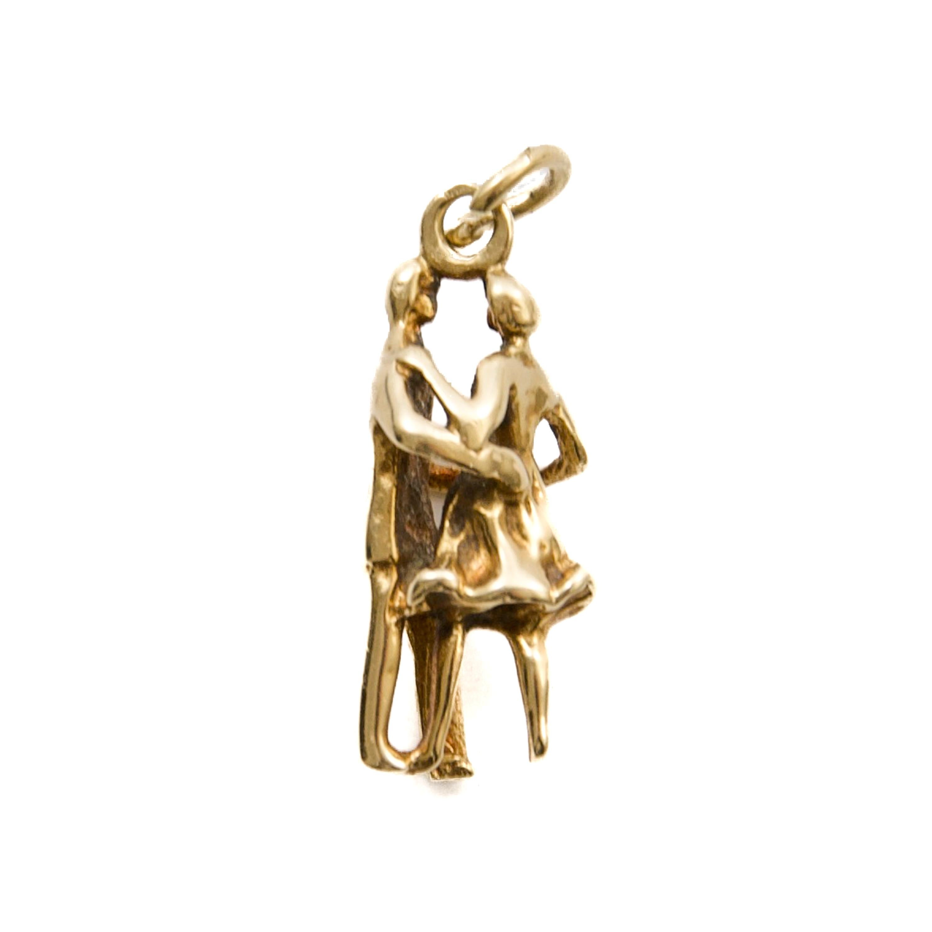Cette charmante breloque vintage capture l'élégance et le romantisme d'un couple dansant, magnifiquement réalisé en or 14 carats. Le design complexe donne vie à la scène, avec des personnages détaillés posés gracieusement au milieu de la danse,