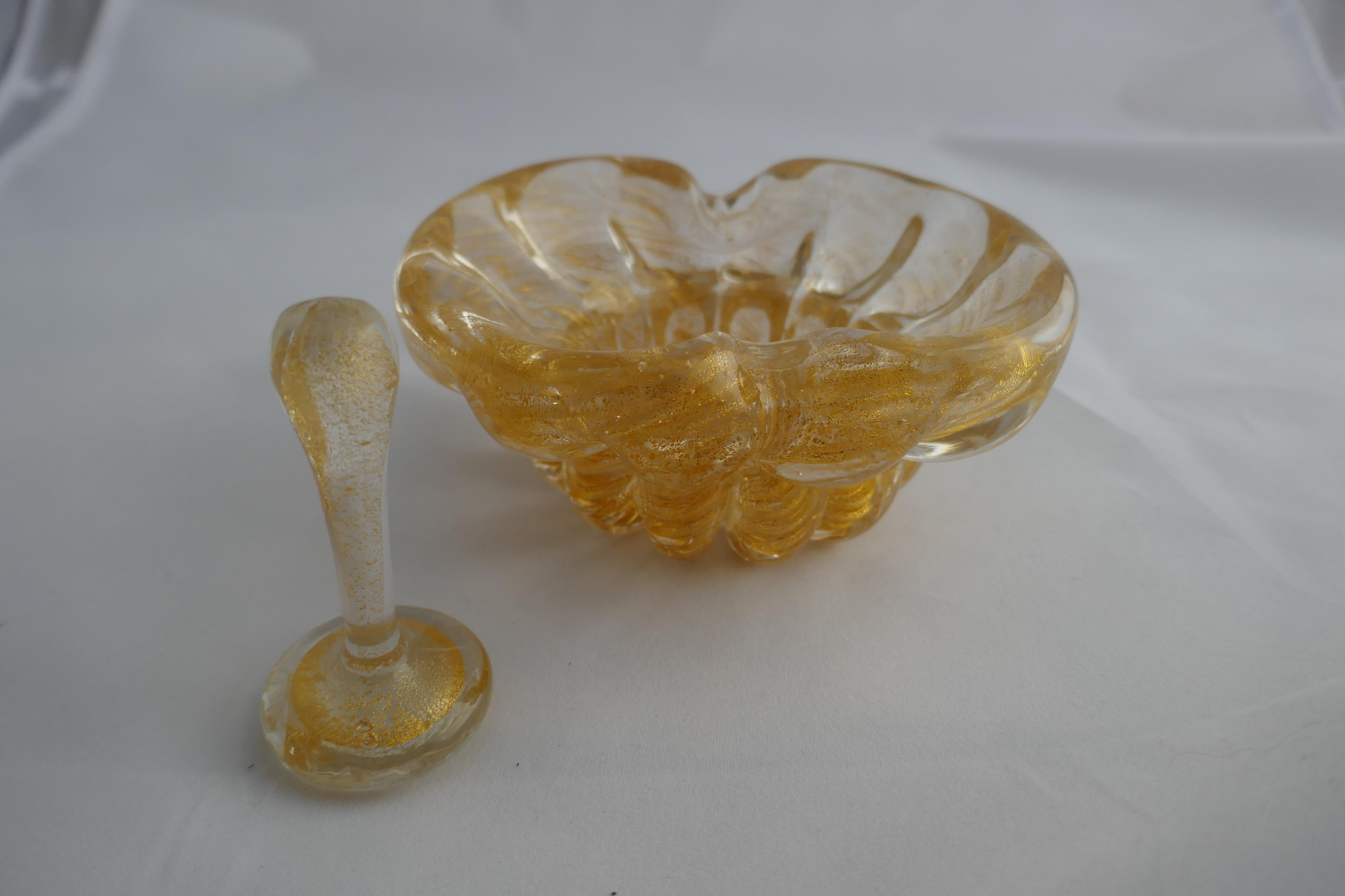 Vintage gold dust Archimede Seguso Murano ashtray or bowl with pestle


Elegant bowl has a waisted oval and fluted shape, with grooves each side to hold a cigarette 
It is profusely decorated with gold leaf and gold dust inclusions as is the