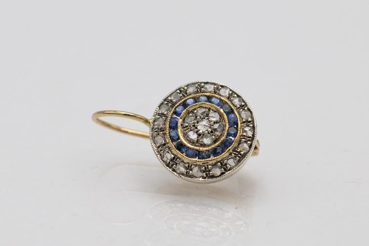 Round gold earrings with antique-cut diamonds and sapphires.

Earrings made of 14 carat yellow gold with 800-900 silver elements.

They are decorated with a total of 46 old rose-cut diamonds, H-F color and SI-I2 clarity. The weight of the diamonds