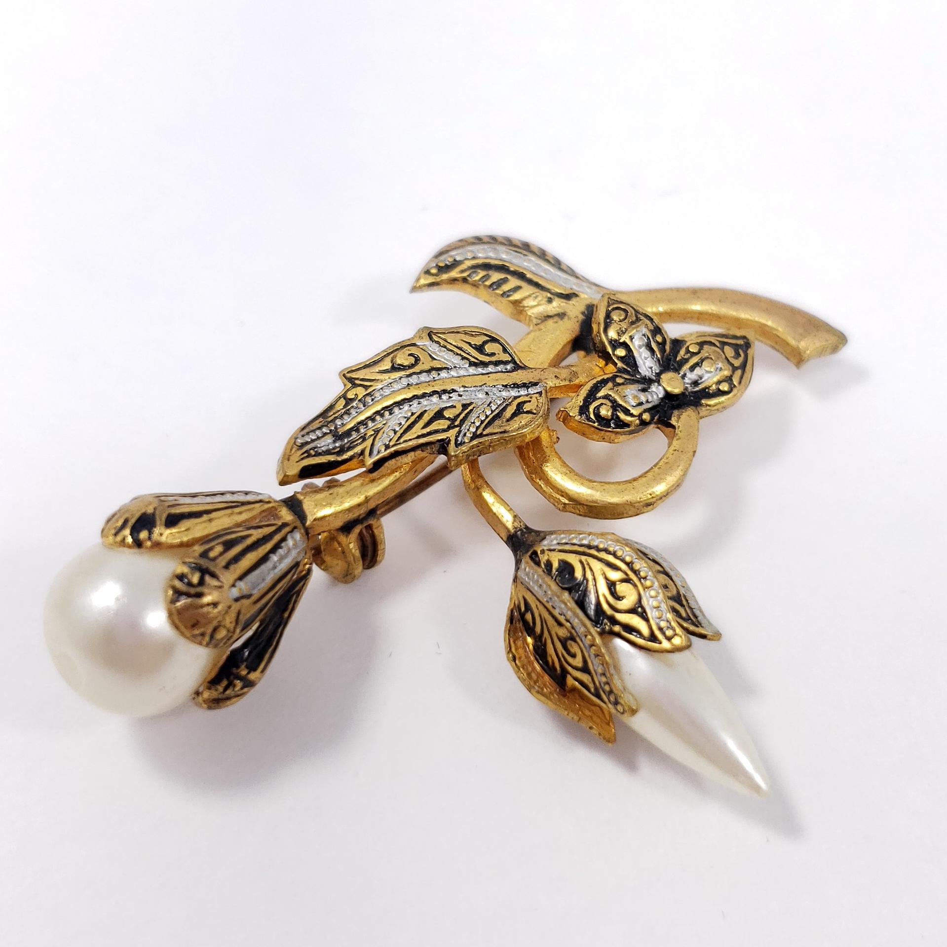 A touch of subtle elegance - this luxurious gold-plated pin brooch features two faux pearls and black enamel accents.