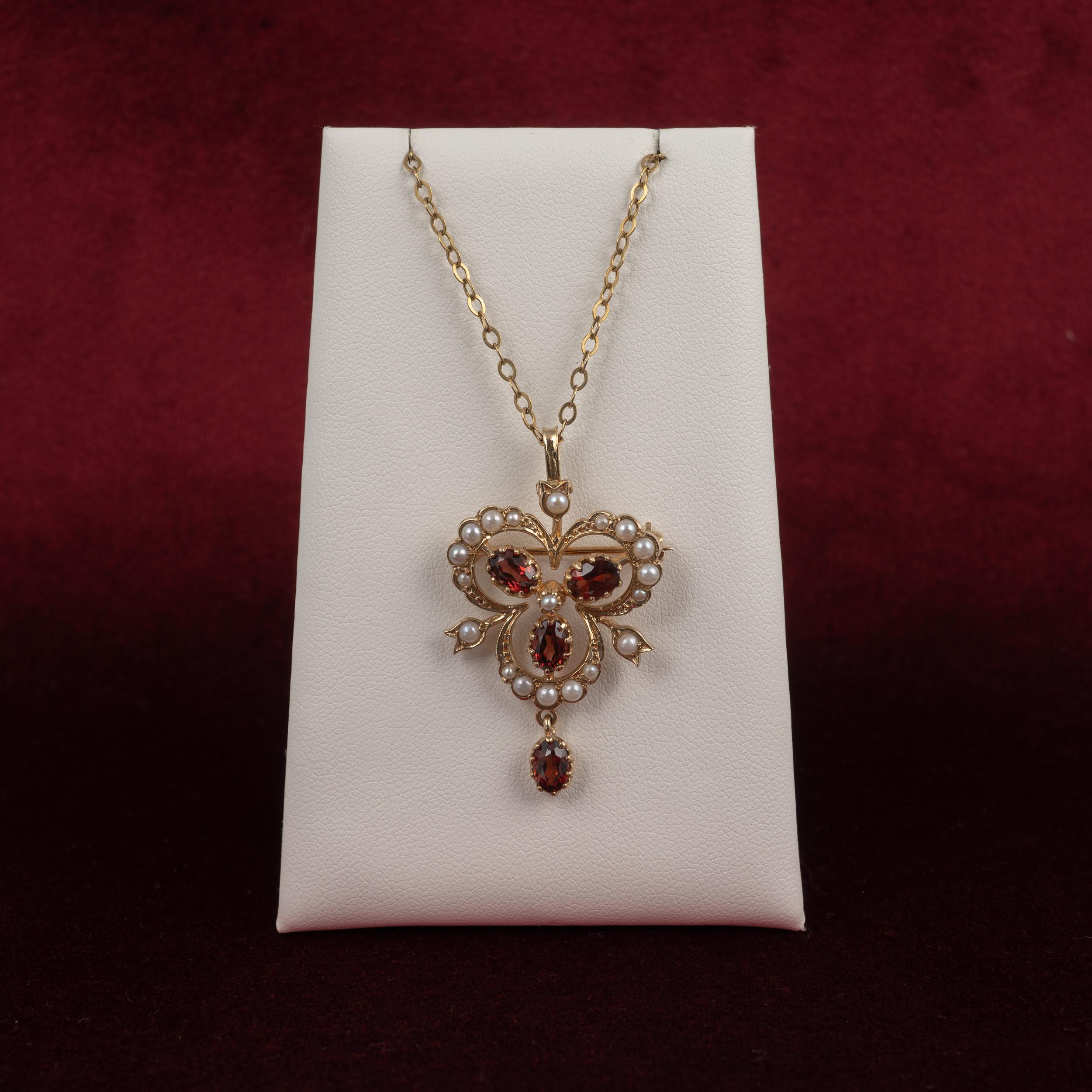 A beautifully presented garnet and pearl. Trefoil shape. pendant brooch which can be worn as a pendant or a brooch, features 3 oval garnets and 16 complimenting seed pearls graduated around the scrolled frame, set to the center and also inside 3