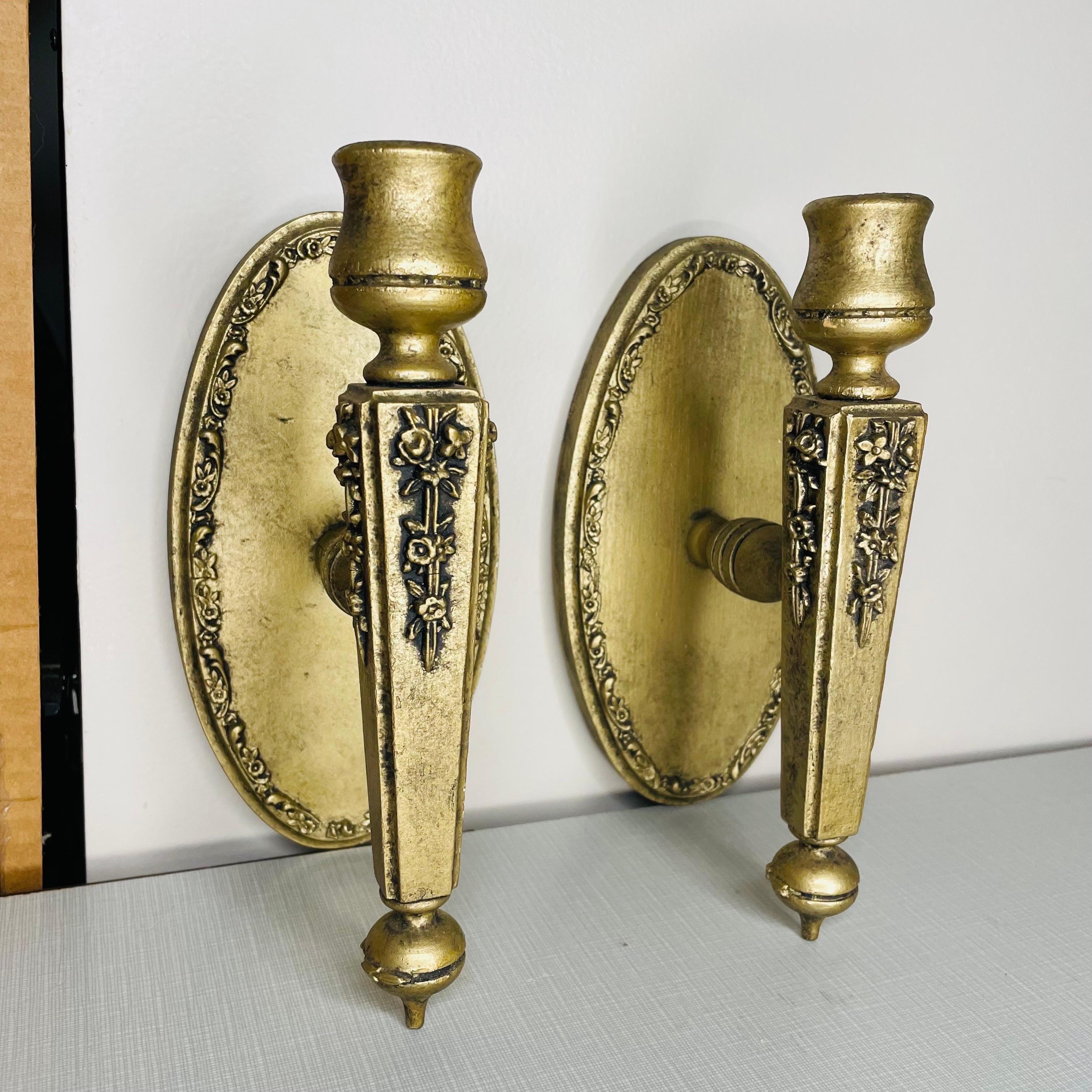Pair of giltwood wall sconces that appear to have been hand carved. All pieces are wooden aside from one nail in the back of each to secure the sconce to the backing and the metal piece that is affixed to the backside for hanging on the wall. Both