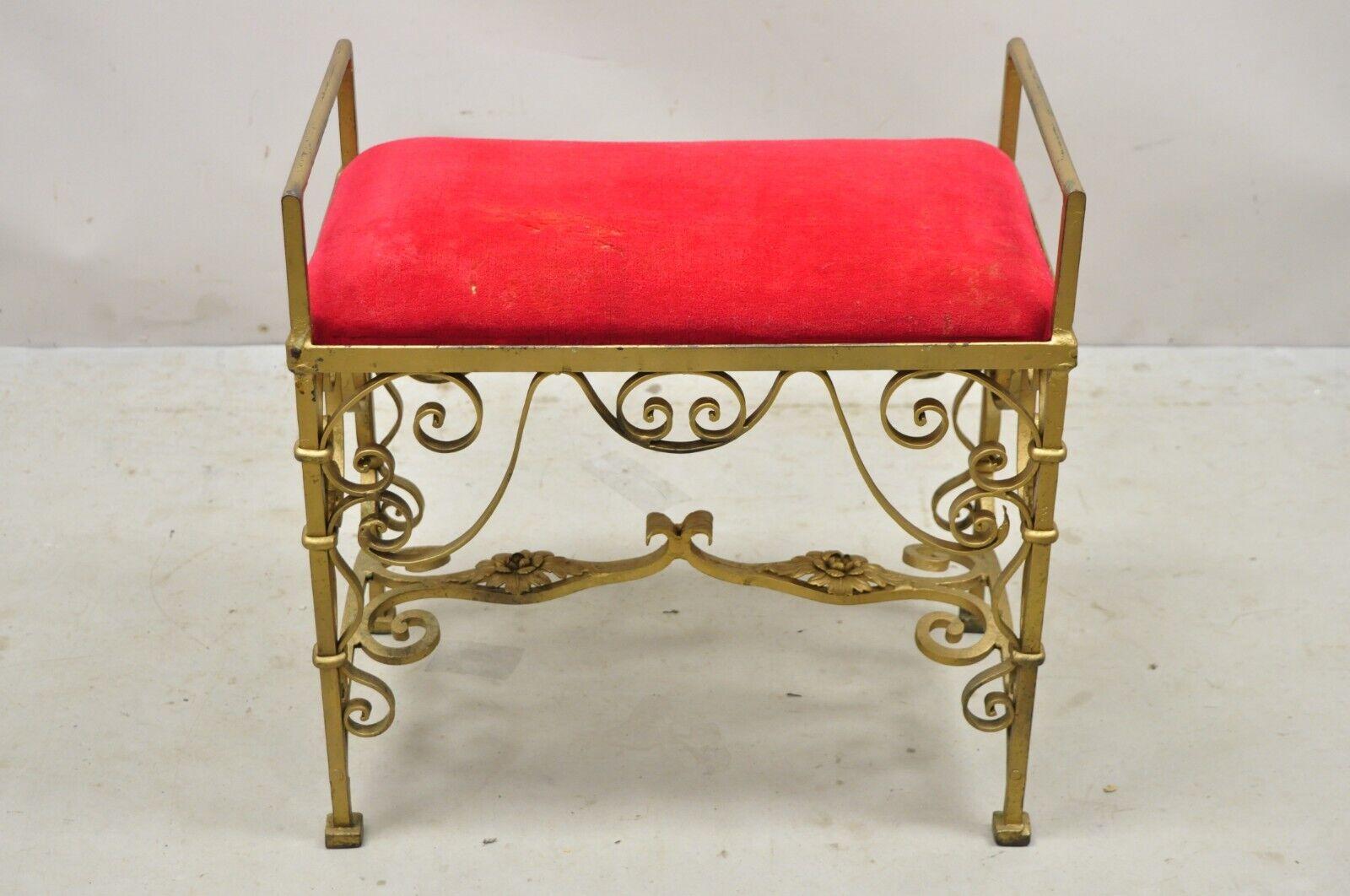 Vintage Gold Hollywood Regency Gothic Scrolling Iron Vanity Bench Seat Stool. Item features a heavy iron frame, distressed gold finish, ornate scrollwork, red upholstered seat, very nice vintage item, quality craftsmanship, great style and form.