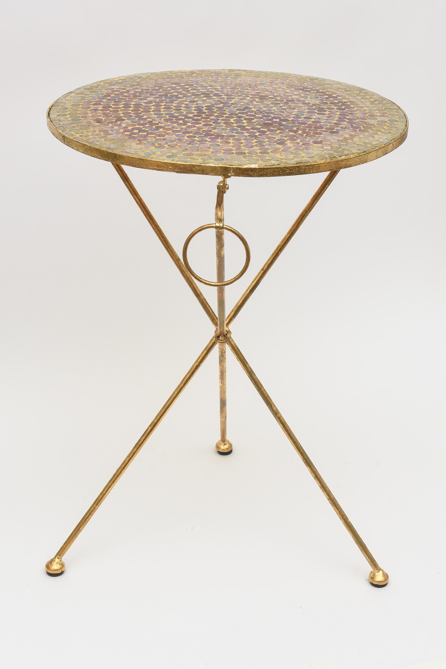 This amazing vintage 1960's tripod side or end table is American.  It has a beautiful glass mosaic top that has iridescent colors of circular glass in shades of the subtle colors of  light green,  orange, light pink, purple, yellow, blue and etc.