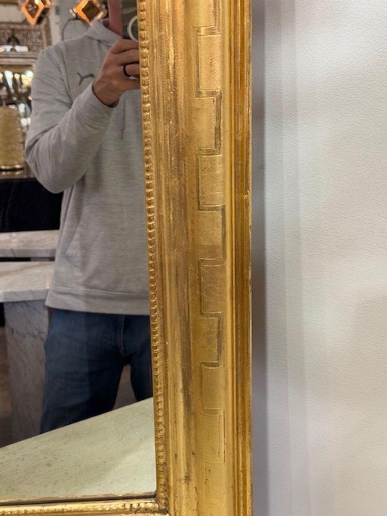 Magnifique miroir Louis Philippe vintage doré, présentant le motif distinctif de la clé grecque. Son cadre orné ajoute une touche de sophistication classique à n'importe quelle pièce, ce qui en fait une pièce de choix pour ceux qui apprécient le