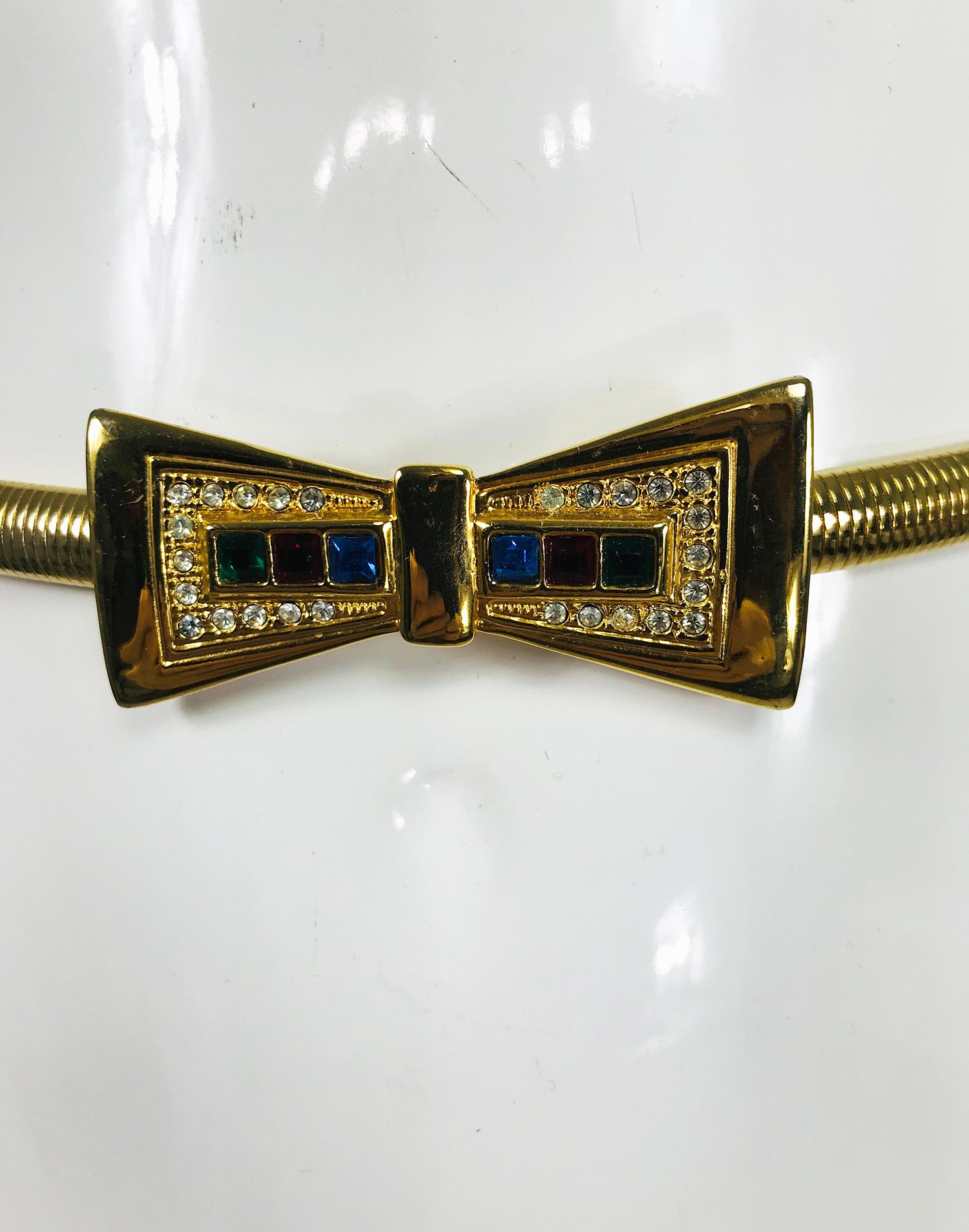 Sleek vintage gold metal rhinestone set bow buckle with expandable/stretch metal belt from the 1960s. The buckle at the front is shiny gold metal each side of the bow inside is set with a surround of crystal rhinestones and a bar of square bezel