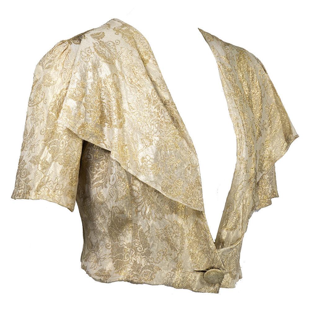 Lamé de brocart métallisé or. Veste courte. Col châle drapé. Fermeture à bouton unique. Manches courtes. Entièrement doublé. Soie crème. Léger ternissement sur l'ensemble de la pièce. Très bon état.


Informations complémentaires :
Dimensions :