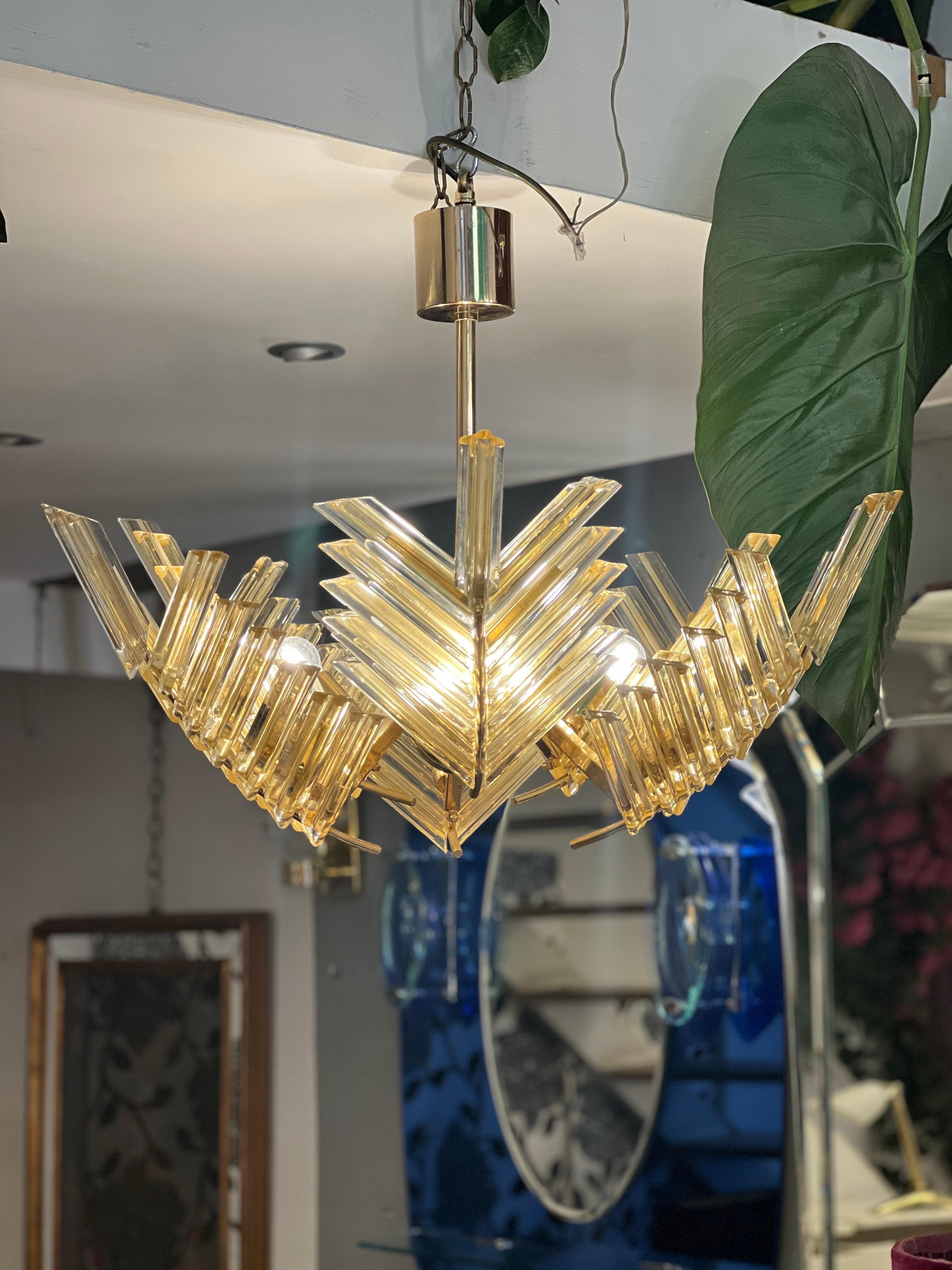 Vintage Murano gold-leaves glass palm chandelier. It is composed of small sections of gilded glass that form a palm leaf shape and has a brass structure. The chandelier features six light bulbs.

