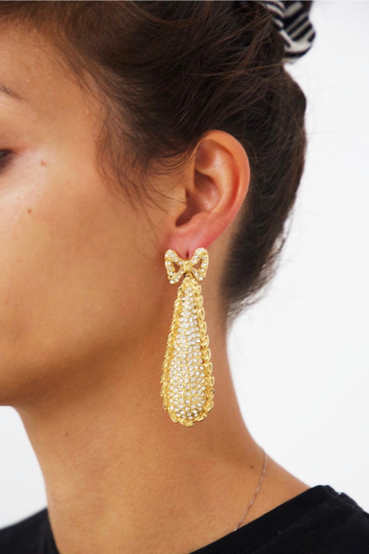 Beautiful pair of gold-plated metal alloy earrings dating from the 1980s, made in France.
The earrings are made of a fine gold-plated metal and have a dangling shape.
At the lobe is a little bow from the center of which the dangling body of the