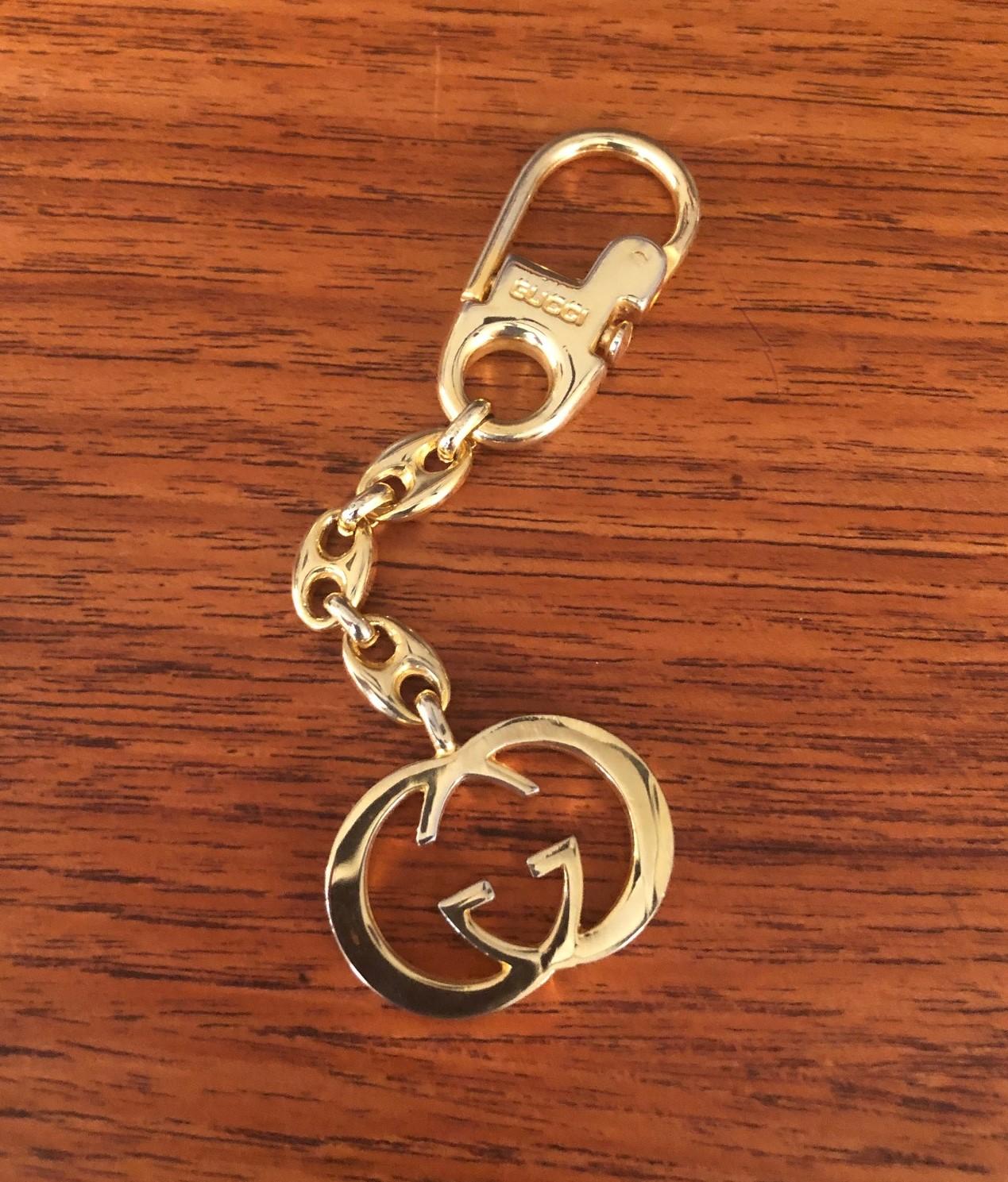 Vintage gold-plated logo keychain by Gucci, circa 1980s. This timeless piece, with interlocking 