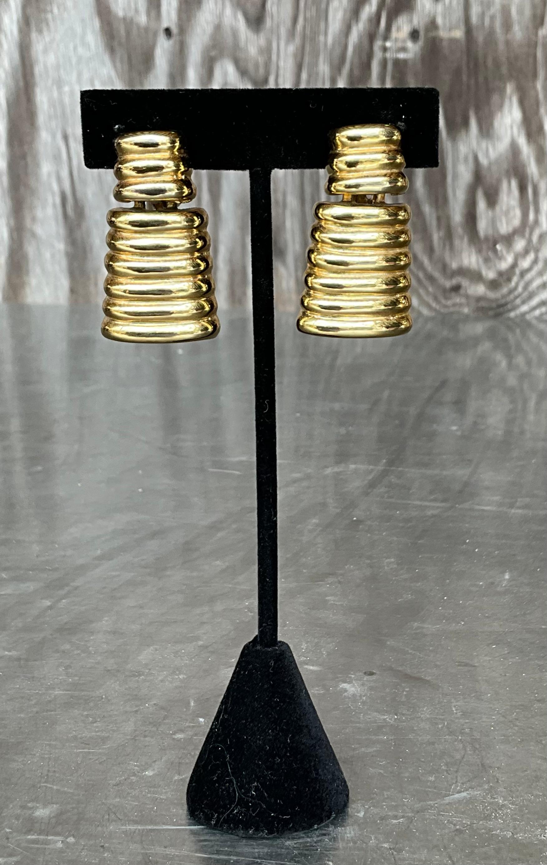 Diese goldfarbenen, gerippten Ohrringe im Vintage-Stil strahlen mit ihrem strukturierten Design und der reichen Goldoberfläche zeitlose Eleganz aus. Die aus hochwertigem goldfarbenem Metall gefertigten Ohrringe haben eine gerippte Struktur, die