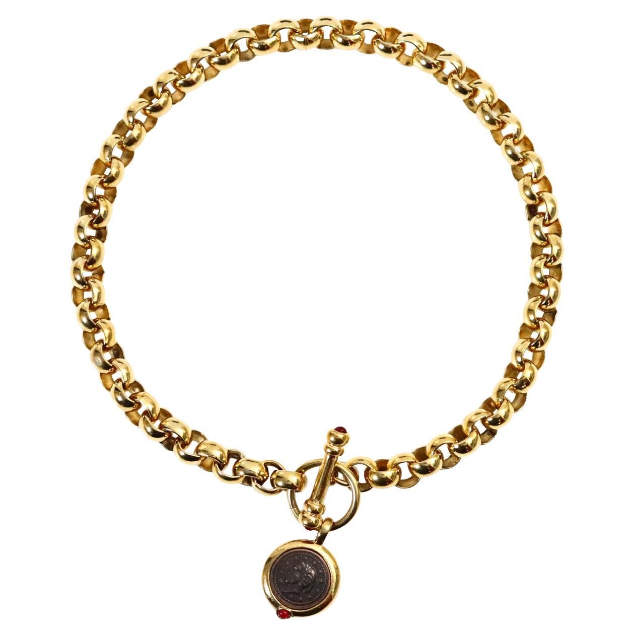Vintage Gold Rollo Chain with Toggle and Dangling Coin Necklace Circa 1990s.  The toggle has red cabochons and the coin has black imprinted  dangling face. This is a classic necklace that is heavy and well made.  Each side of the toggle also has the
