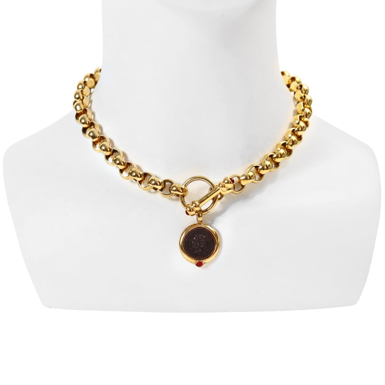 Vintage Gold Rollo Chain with Toggle and Dangling Coin Necklace Circa 1990s.  The toggle features red cabochons, and the coin has a black, imprinted, dangling face.

This is a piece that remains in style and always looks great.  The necklace part is