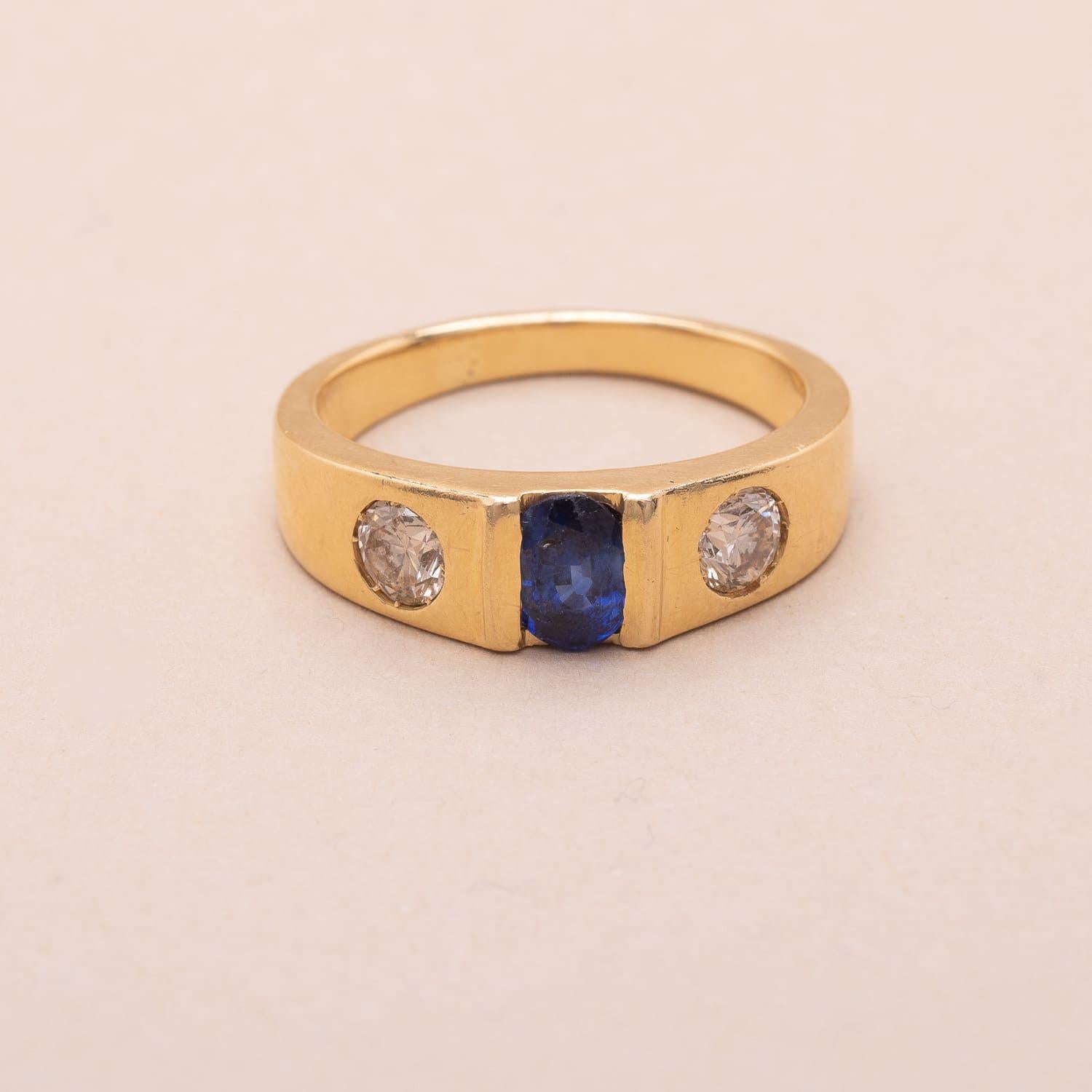 18K gold three-stone ring set with an oval-cut sapphire surrounded by two brilliant-cut diamonds 

Sapphire's estimated weight : 0.60 carat 
Diamonds' estimated weight : 0.66 carat total

Estimated diamonds characteristics : Color GH, Purity