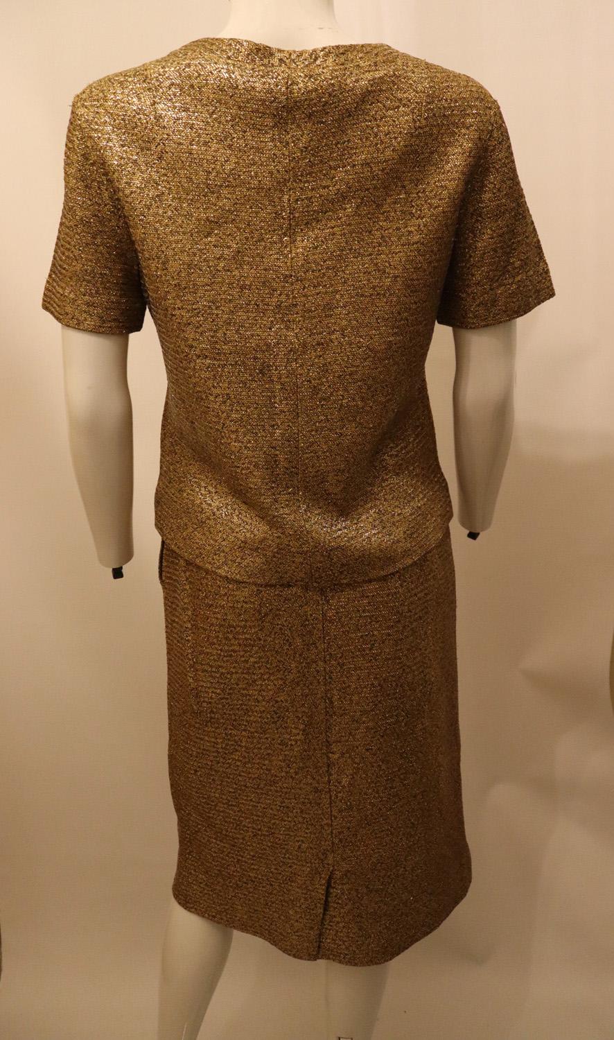 A chic vintage skirt suit by Claret. In a wonderful fabric with a gold, silver and black background.
The top has a v neckline and short sleaves. The skirt has a back zip opening and  5 1/2 '' slit on the right hand side. They look great worn