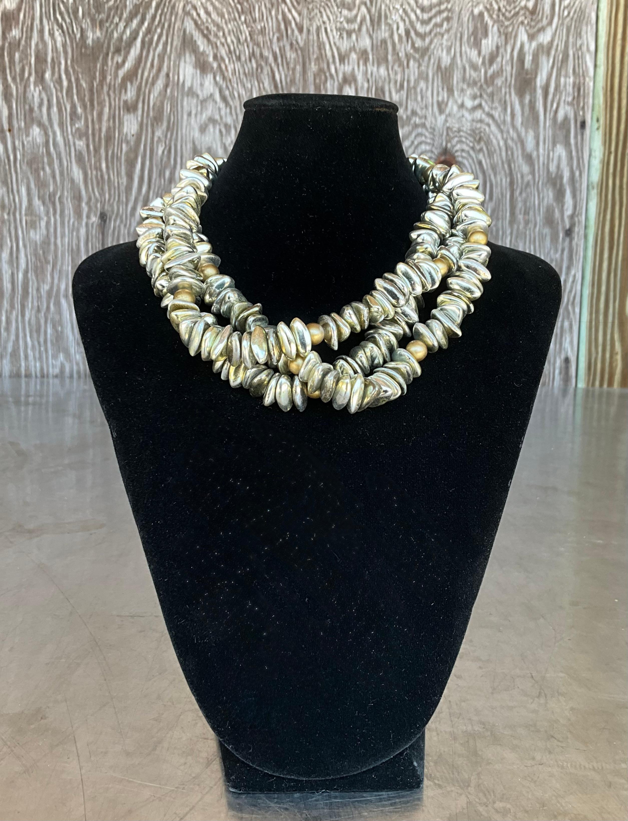 Questa collana vintage in oro e argento a più fili è una straordinaria fusione di eleganza metallica e design senza tempo. Caratterizzata da più fili di perline disposte in modo intricato nei toni scintillanti dell'oro e dell'argento, questa collana