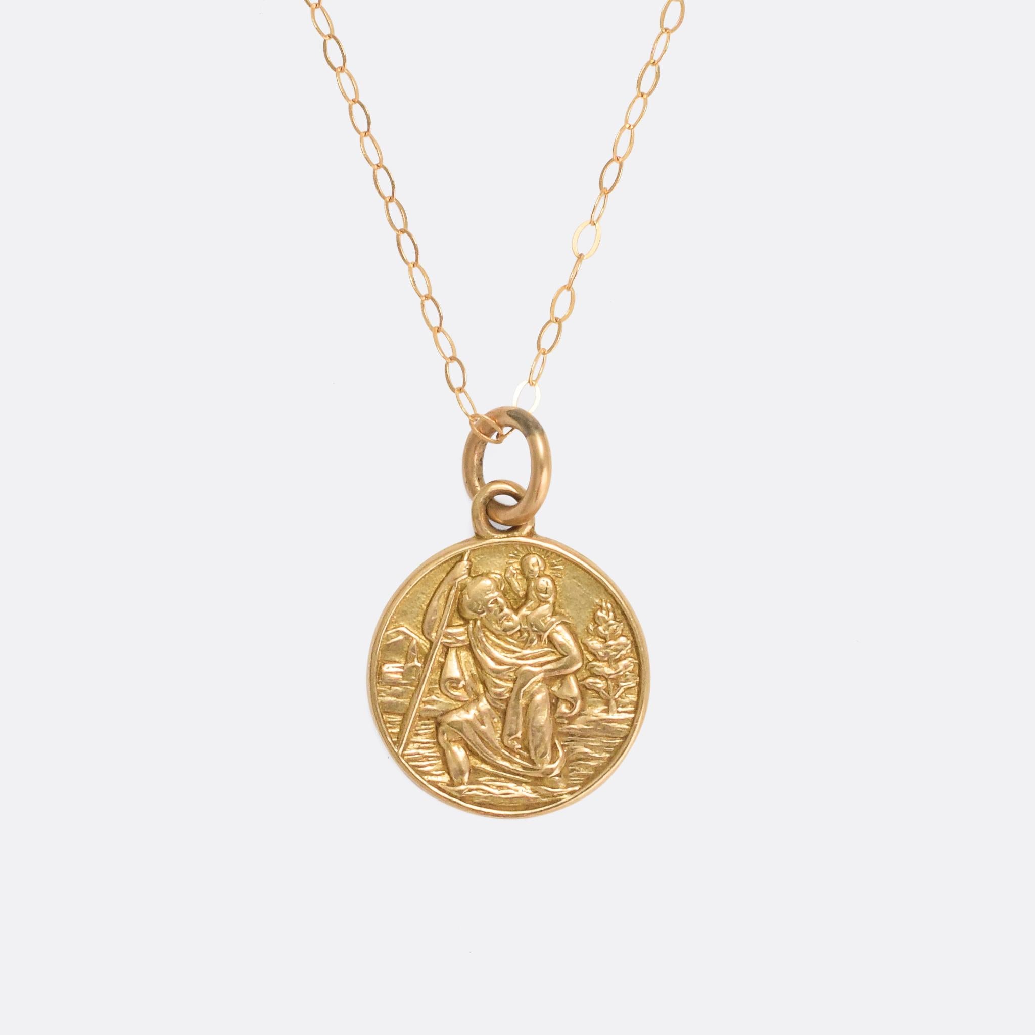 A sweet vintage St. Christopher in 9 karat yellow gold. A classical representation of Jesus crossing the river on Christopher's back, in relief, and to the reverse it bears the inscription: 
