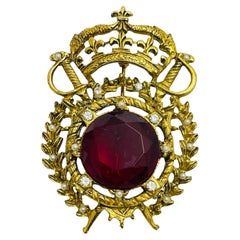 Spilla vintage in oro con corona di spade e scudo in vetro con rubino