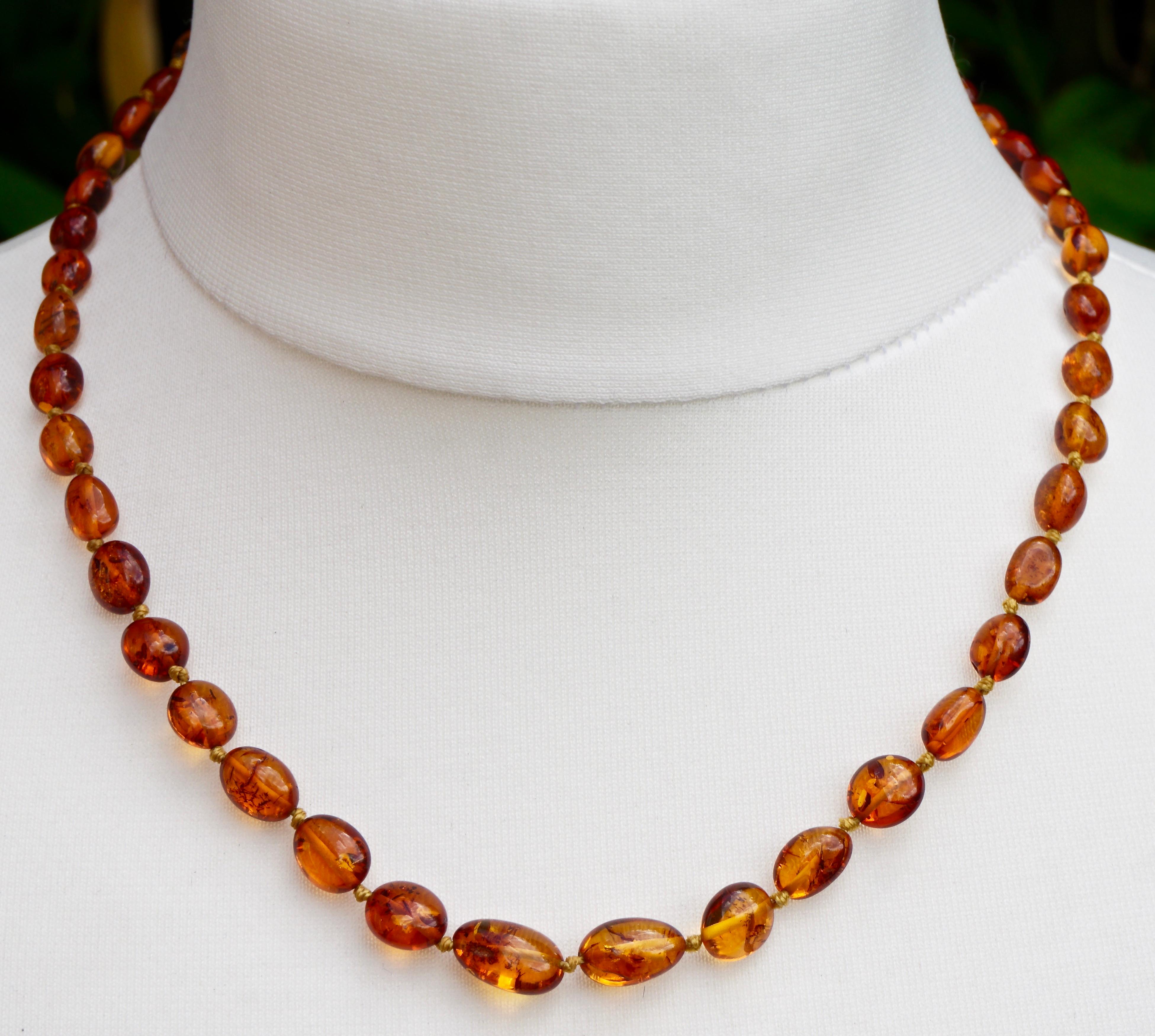 
Dark honey amber necklace with gold tone fittings, featuring lovely highly polished beads, knotted between each bead. Measuring length 49cm / 19.29 inches, the flattish beads are mostly lozenge shaped. They are graduated with the largest bead being