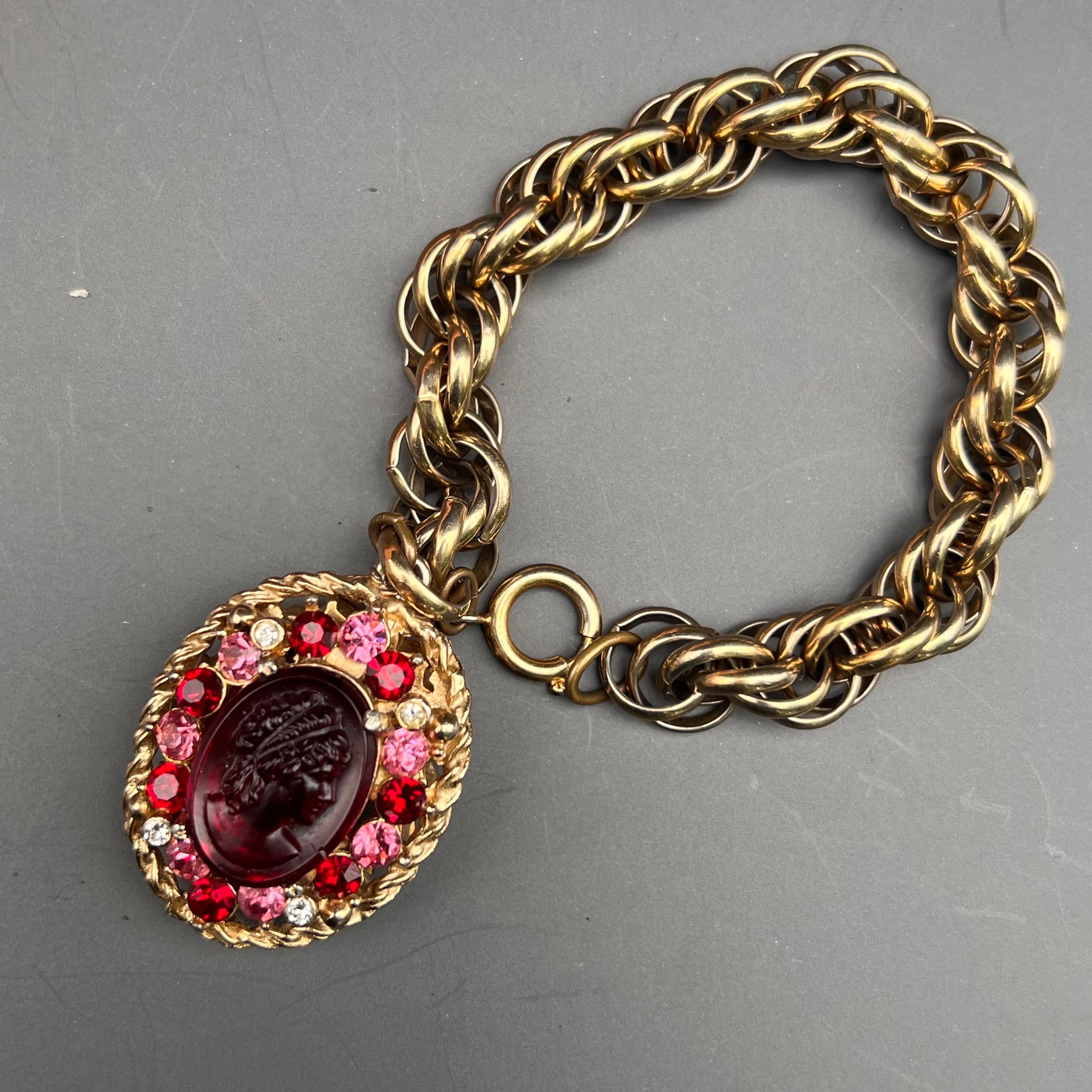 This beautifully crafted vintage gold tone charm bracelet features a large, eye-catching charm/fob adorned with cameo glass cabochons and prong-set rhinestones on both sides. Its elegant design and intricate detailing make it a standout piece that
