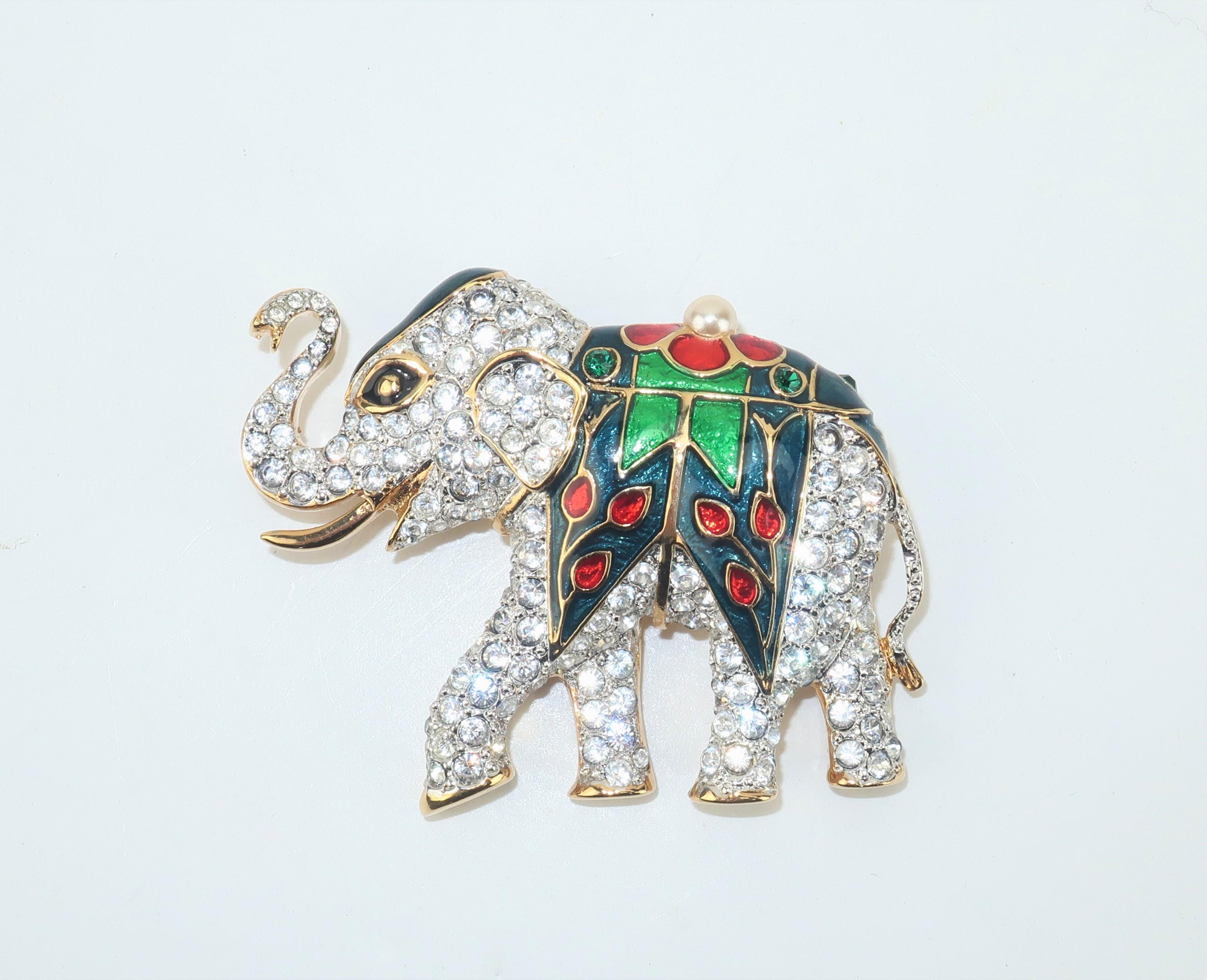 This elephant brooch has a 'sparkling' personality that is sure to add charm to any lapel.  The gold tone elephant is embellished with crystal rhinestones and festooned with blue, red and green enamel and topped with a pearl.  It is outfitted with a