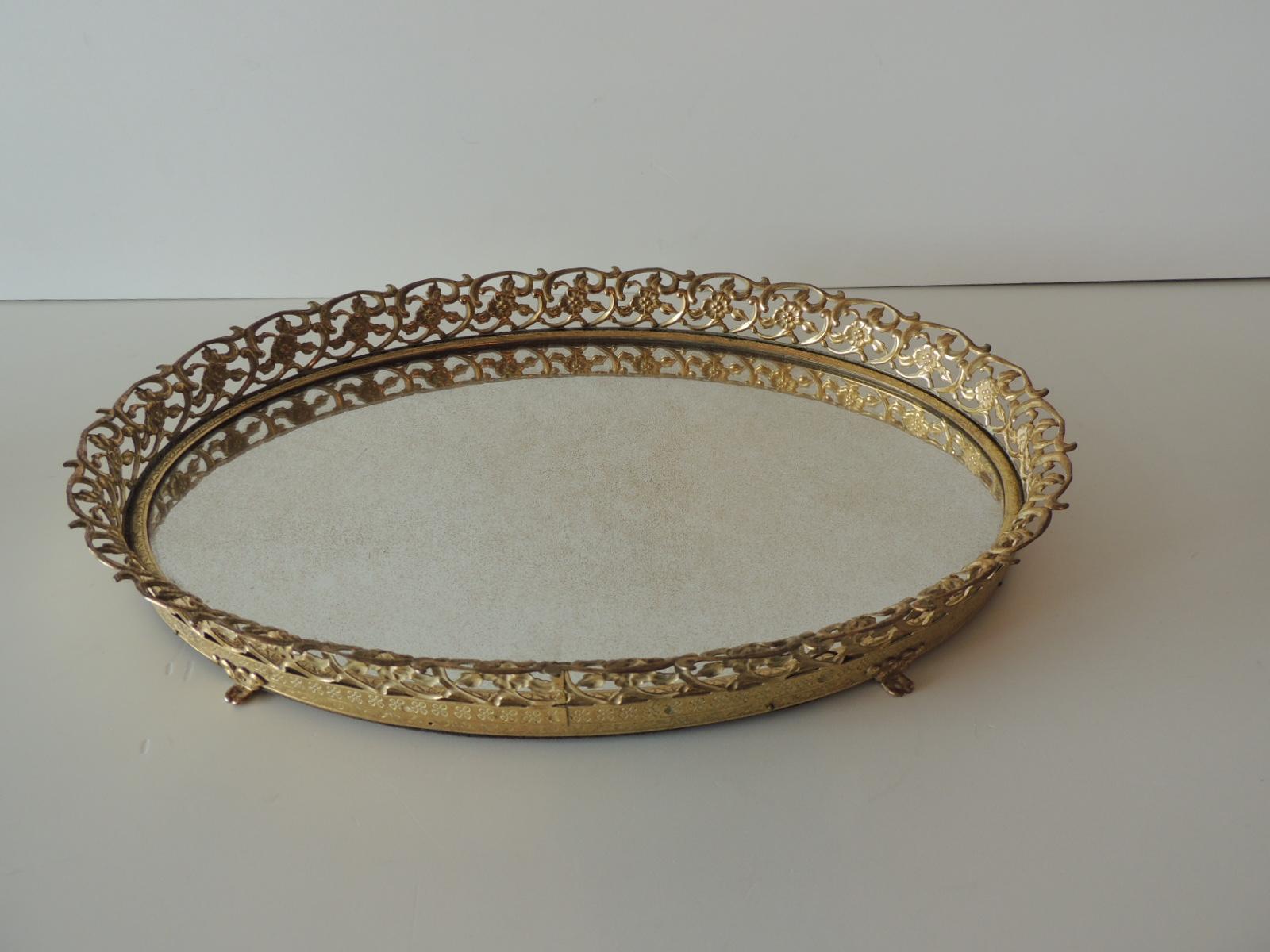 Vintage gold tone filigree oval brass footed vanity tray with mirror
floral pierced tray edge with oval antique finished mirror inset. Felt backing.
Size: 14
