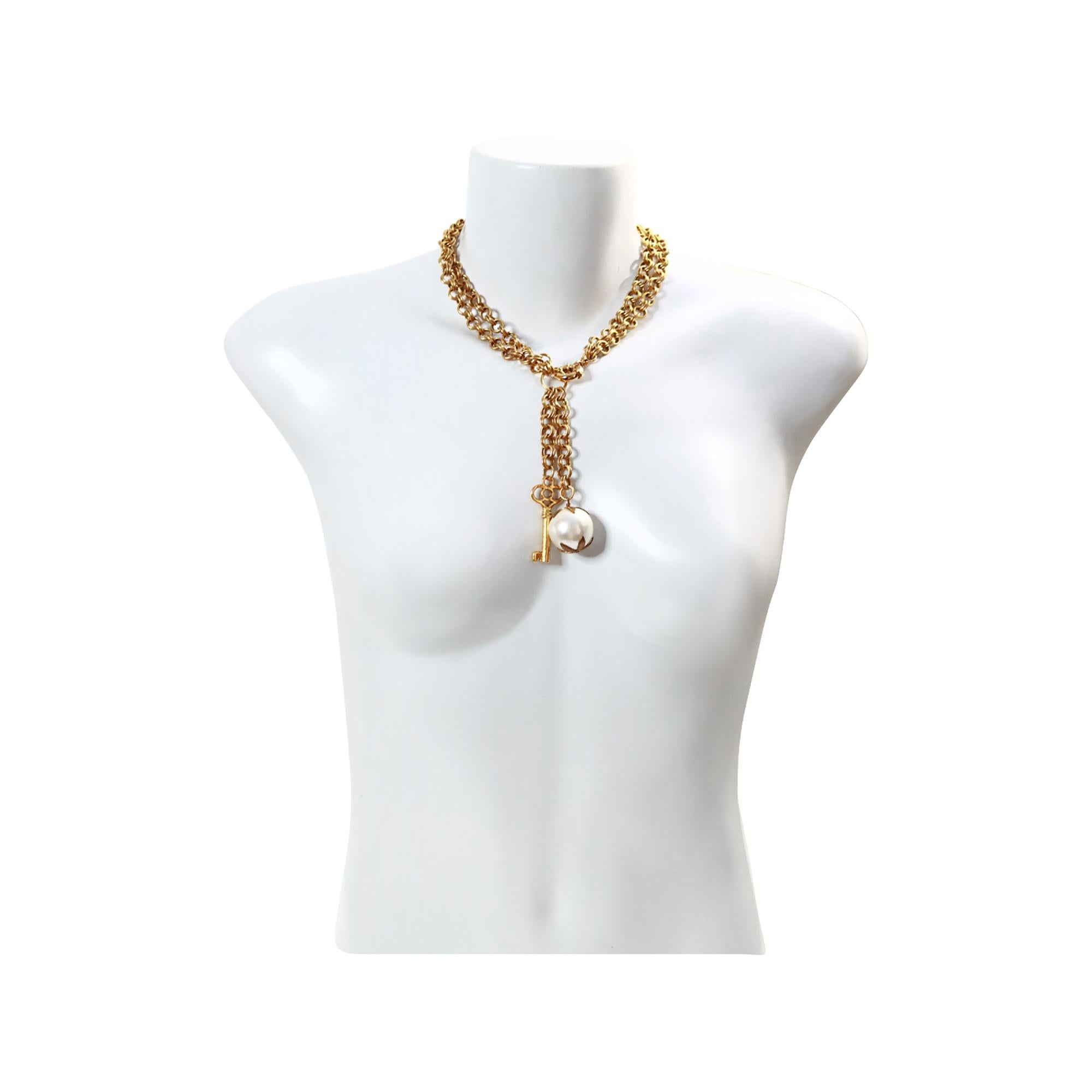 Collana vintage in tonalità oro con chiavi a goccia e perle finte, circa anni '80. È una collana elegante e sostanziosa. La doppia catena, con i suoi pezzi pesanti che penzolano verso il basso, gli conferisce un'aria molto antica, da vecchio mondo,