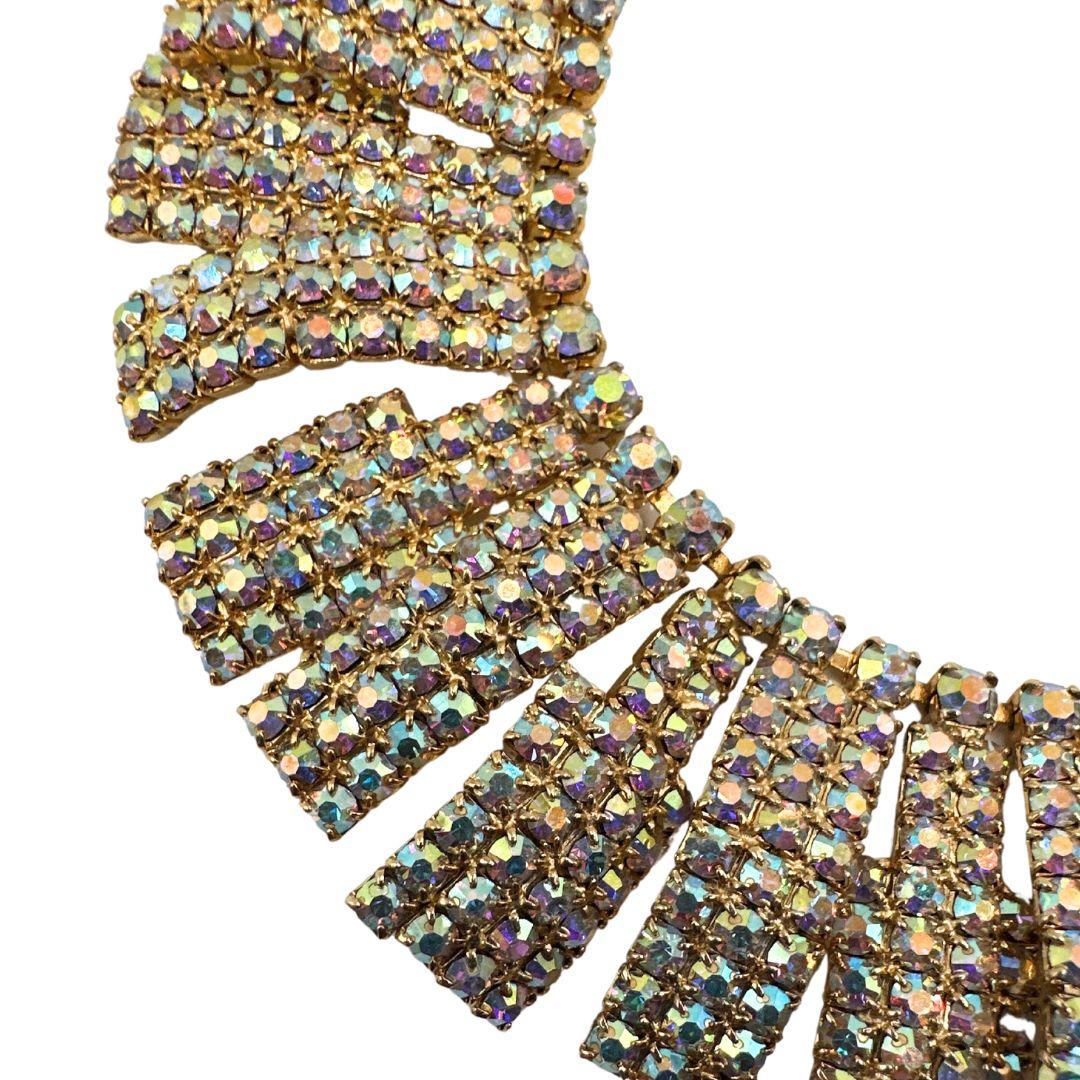 Schmücken Sie sich mit dem Glamour der Art-Déco-Ära mit dieser exquisiten, goldfarbenen Strass-Latz-Halskette im Vintage-Stil. Diese Halskette ist ein wahres Schmuckstück mit mehreren schillernden Strasssteinen, die sorgfältig zu einem eleganten