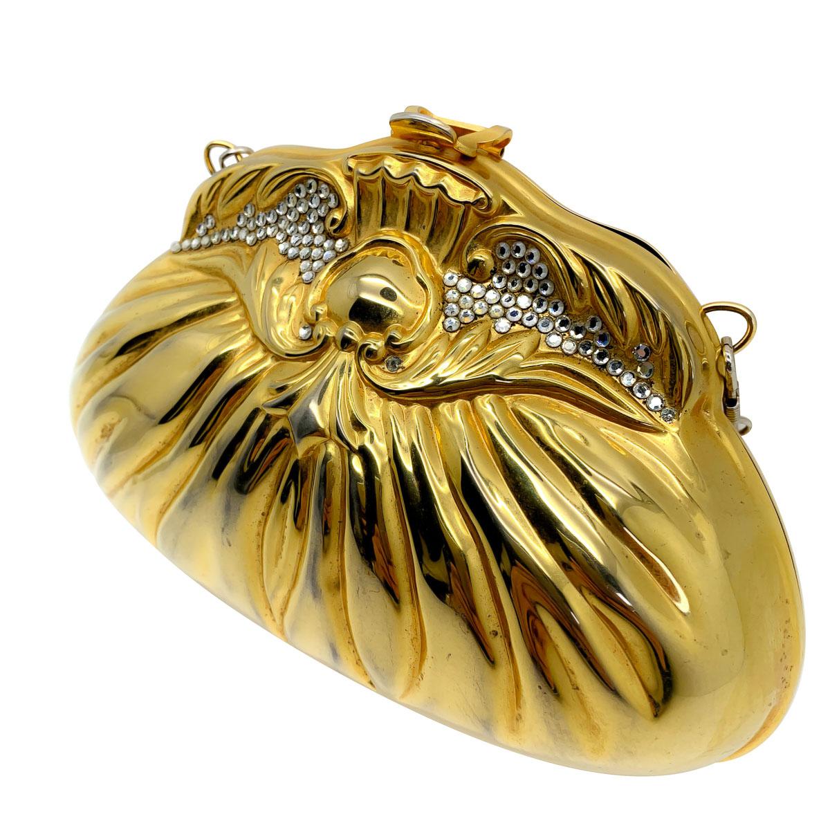 Un sac minaudière vintage en or. Il s'agit d'un sac à main rigide conçu dans le style d'un sac à main en tissu et orné de minuscules cristaux appliqués qui se coordonnent avec la sangle en chaîne métallique de couleur argentée. L'intérieur est