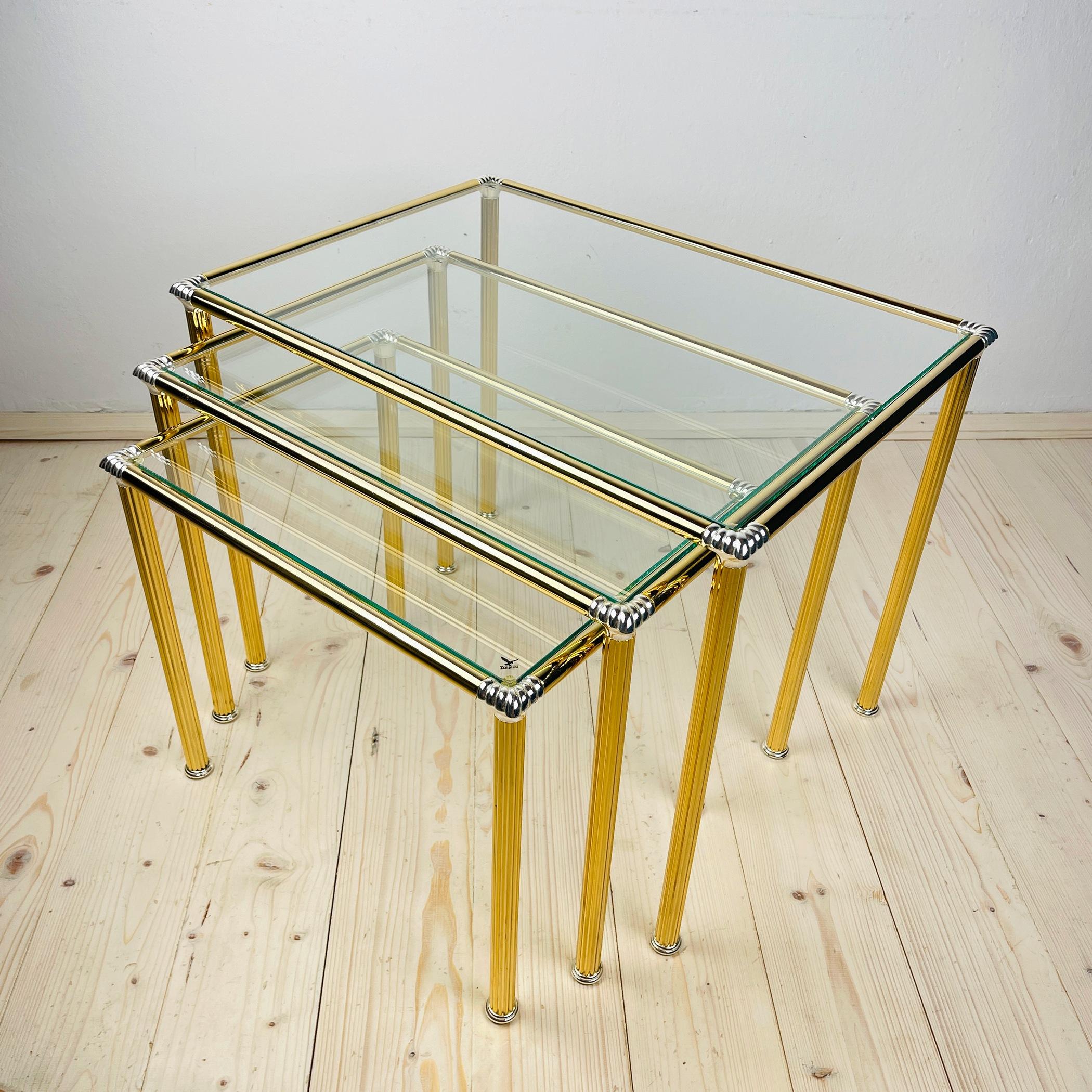 Introducing an exquisite set of 3 Italian vintage design golden nesting tables, each adorned with a beautifully glass top. Crafted to nestle within one another, these tables not only exude modern elegance but also offer practical space-saving