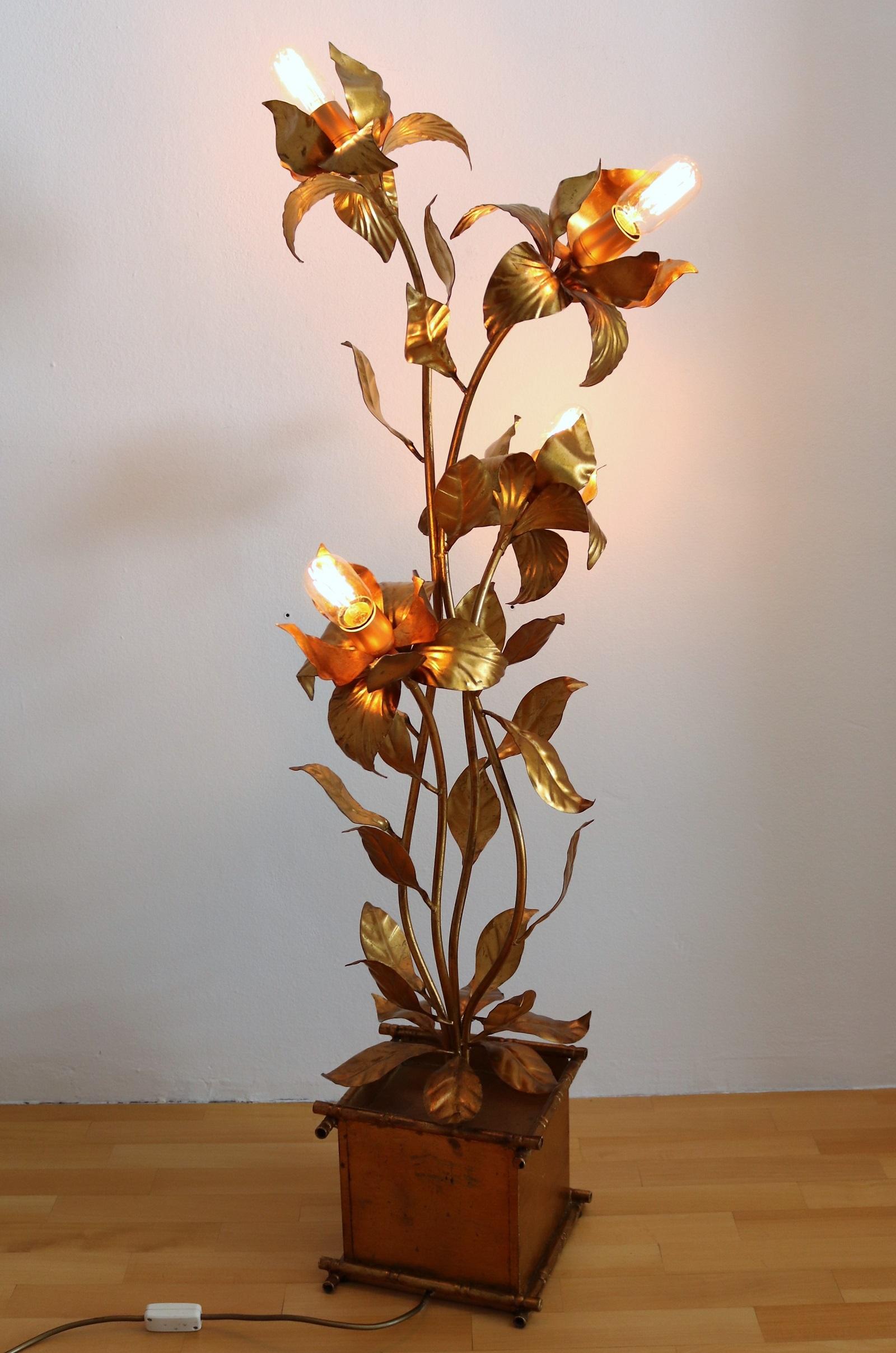 Amazing floor lamp made of gilt metal by Messrs. Kögl, Germany, in the 1970s.
Full Hollywood Regency style.
The lamp is made in the shape of a completely gilt flower pot with plant and 4 long stems with leaves and big lowers at the end.
In the